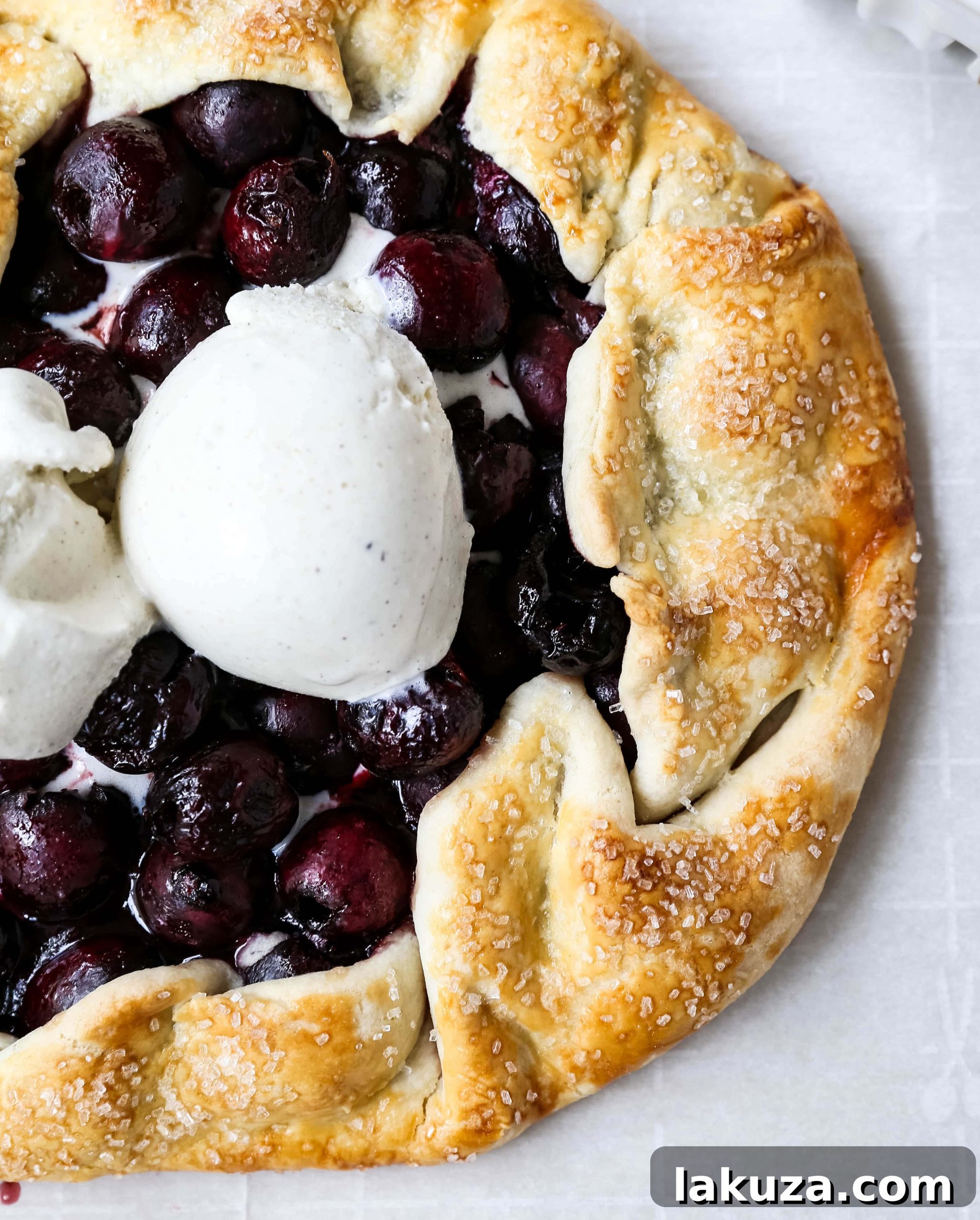 A freshly baked cherry galette, ready to be sliced and served with a side of ice cream.