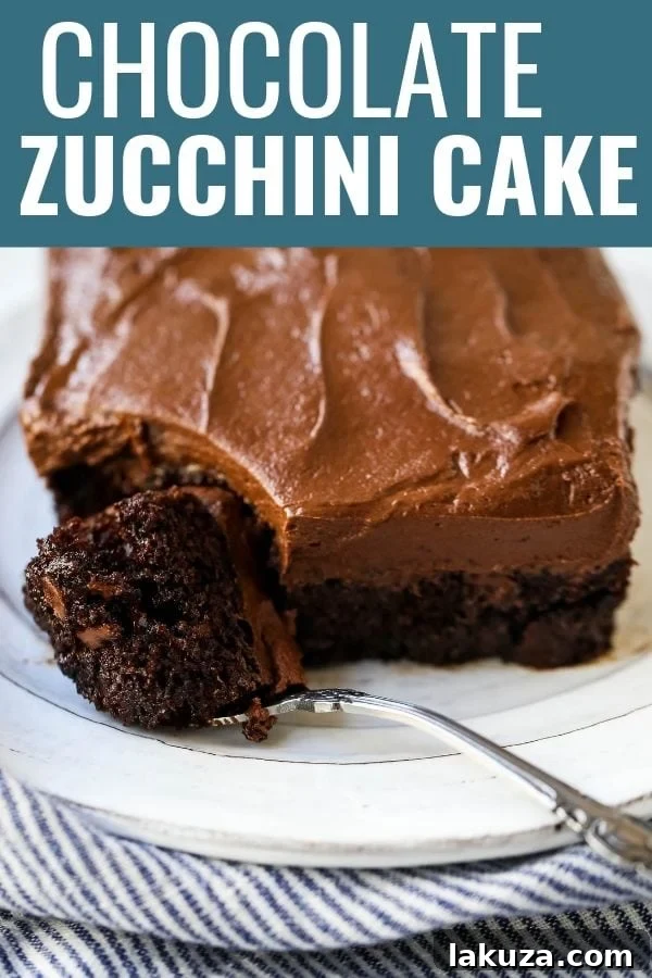 A large chocolate zucchini cake beautifully frosted, sliced and ready to serve on a rustic wooden board.