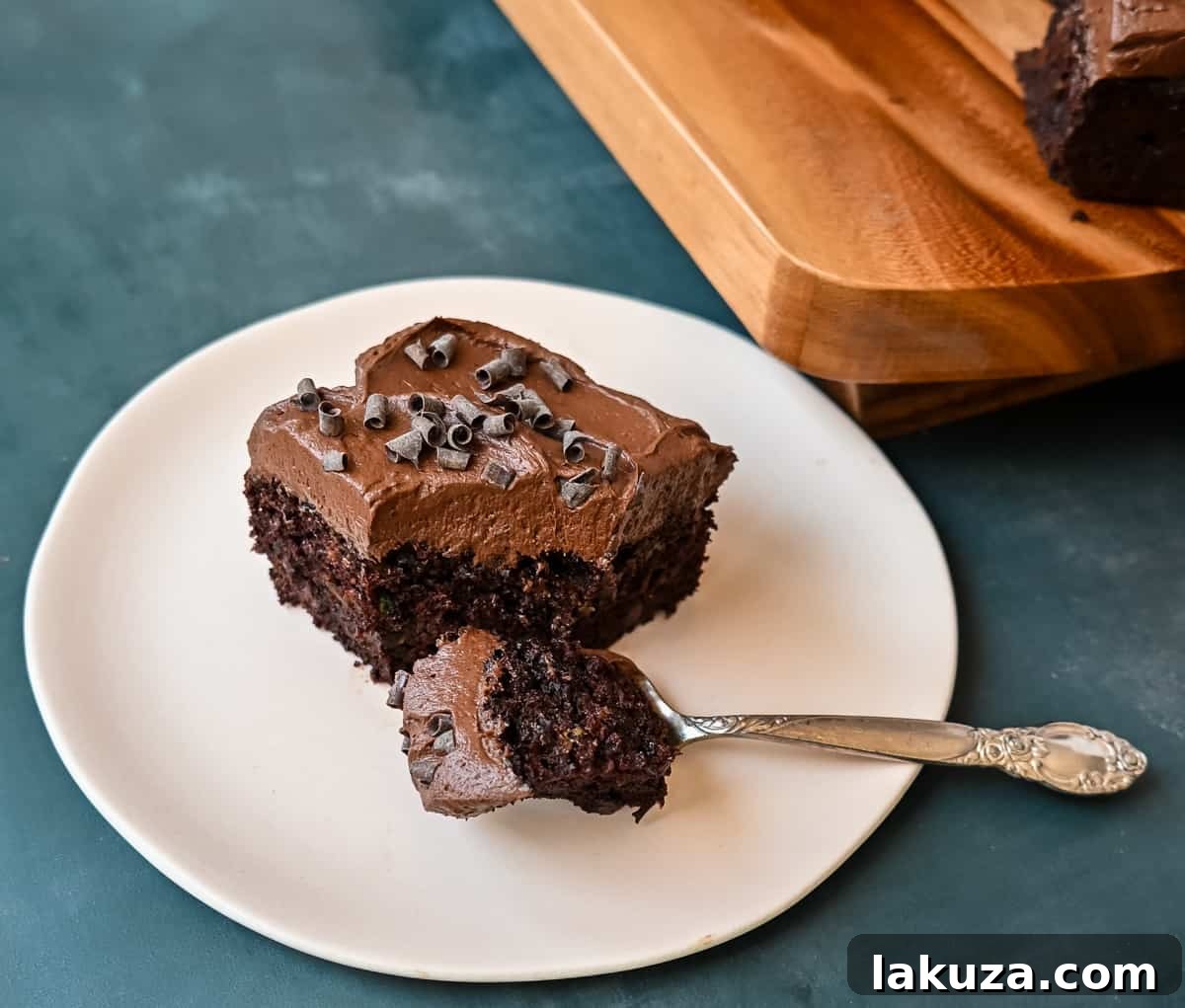 A slice of the best chocolate zucchini cake with chocolate frosting, showcasing its moist texture.