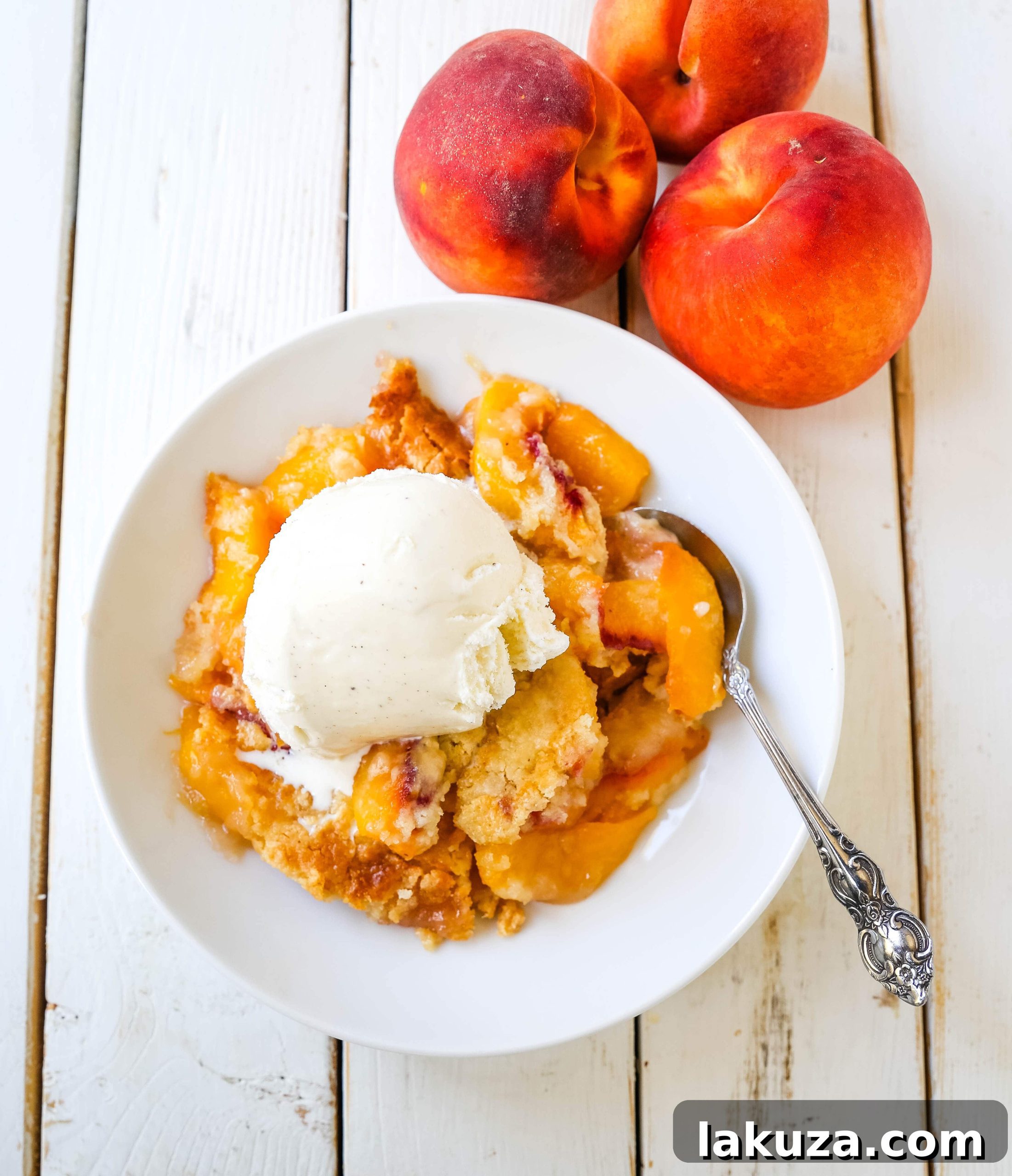 A slice of warm Peach Dump Cake with vanilla ice cream, served on a plate with a fork