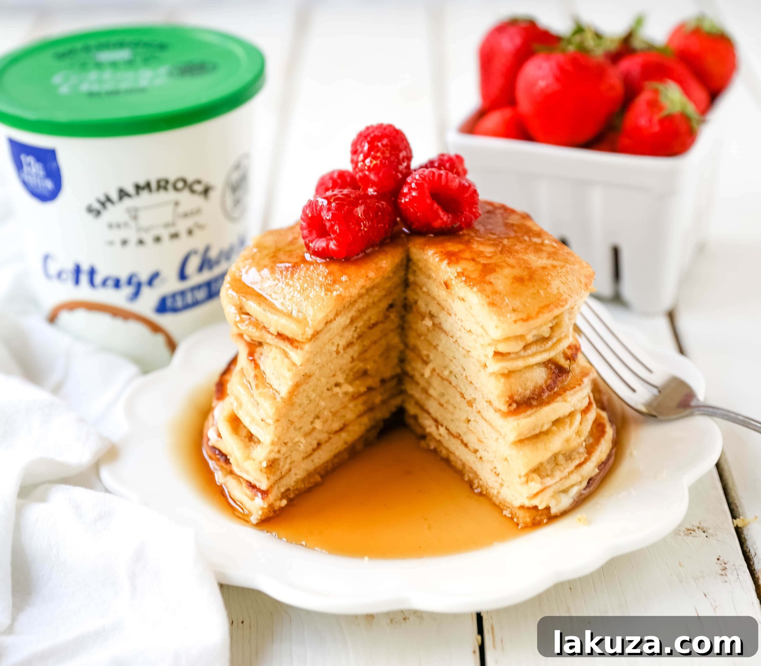 Close-up of freshly cooked cottage cheese pancakes with a drizzle of maple syrup and fresh berries, ready for a nutritious breakfast.