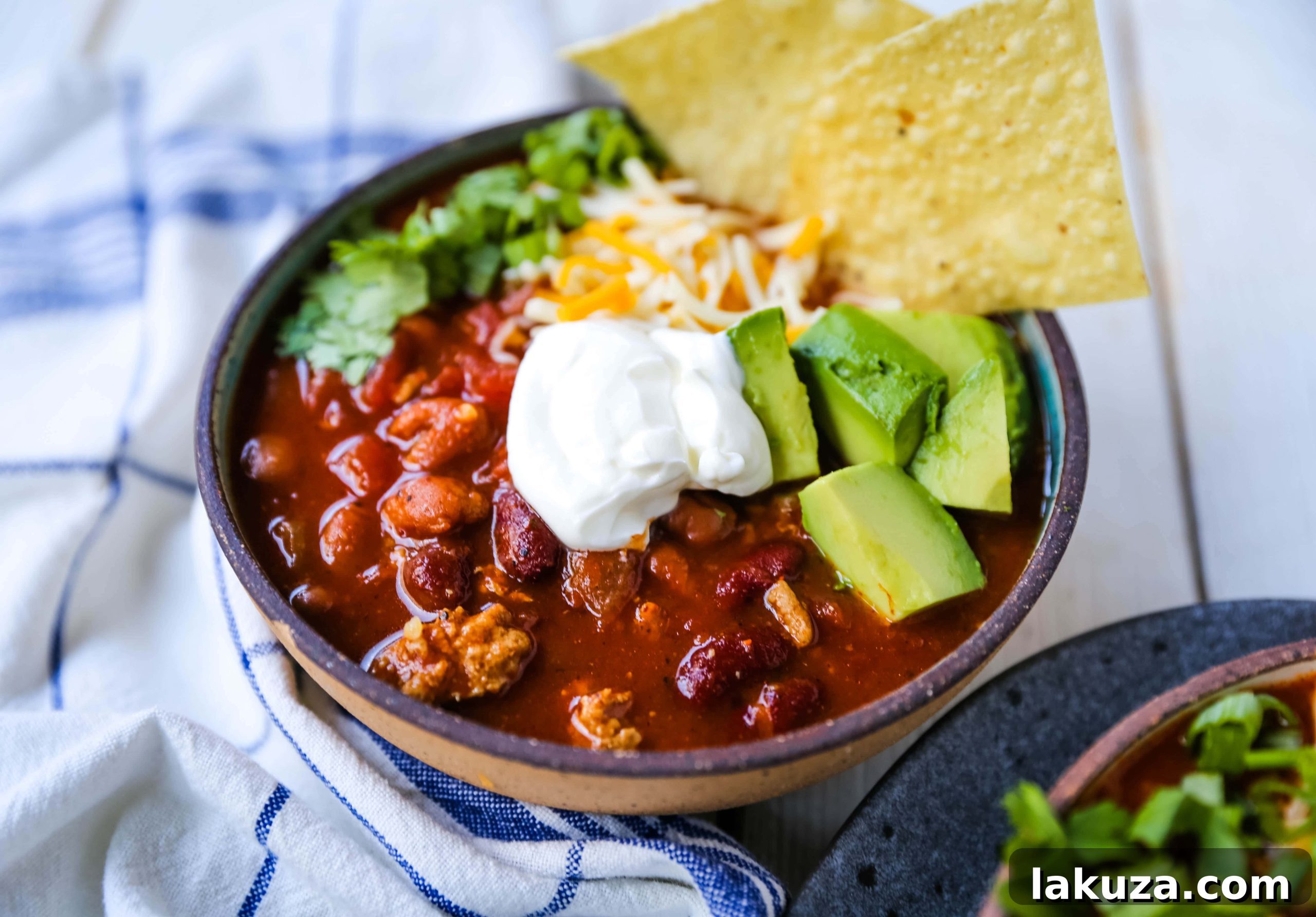 Close-up of a rustic spoon scooping a generous portion of hot turkey chili from a large pot