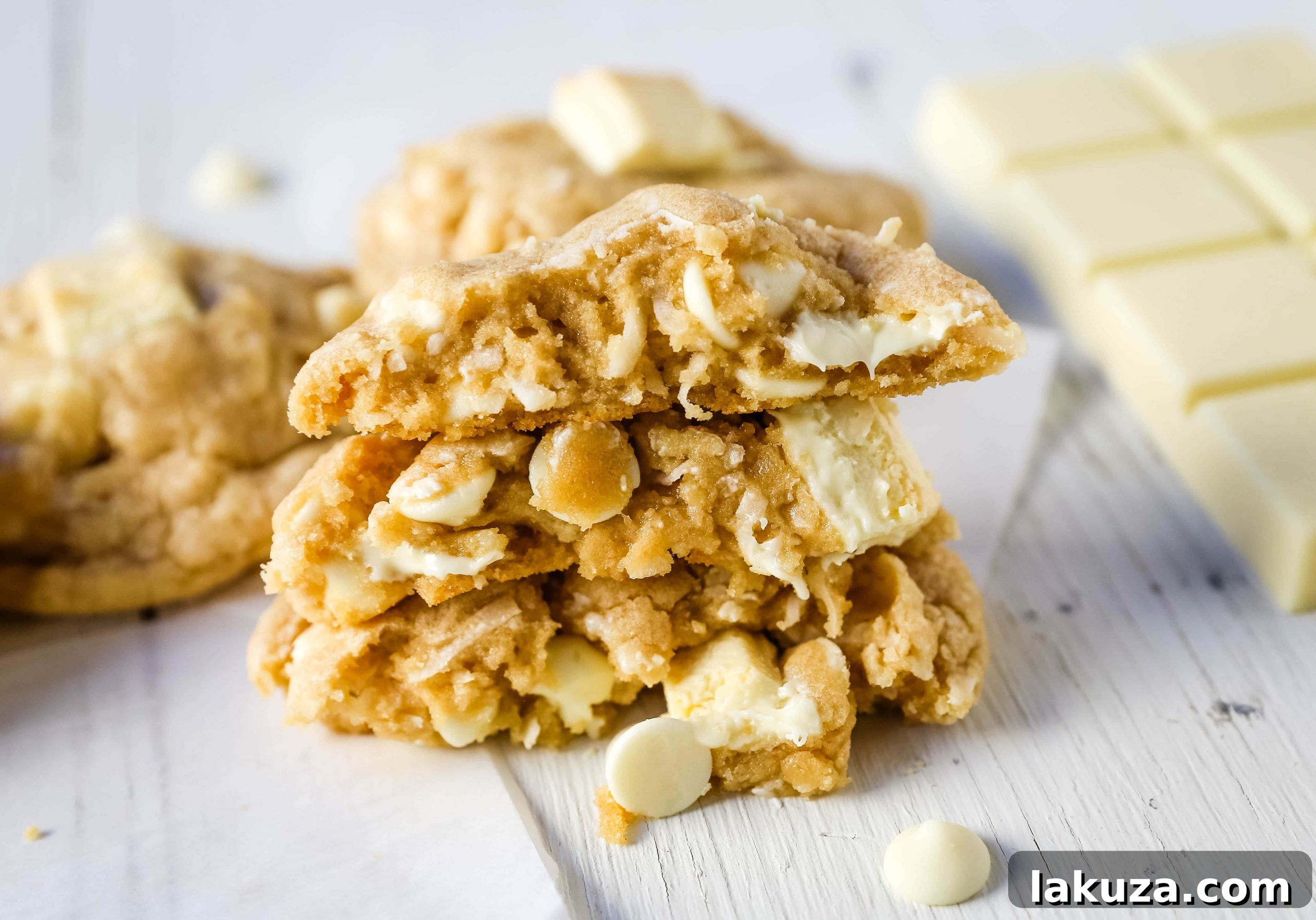 Tropical White Chocolate Coconut Delights 4 A hand reaching for a delicious White Chocolate Coconut Cookie from a parchment-lined baking sheet, still warm from the oven.
