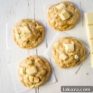 A stack of soft and chewy White Chocolate Coconut Cookies, glistening with melted white chocolate.
