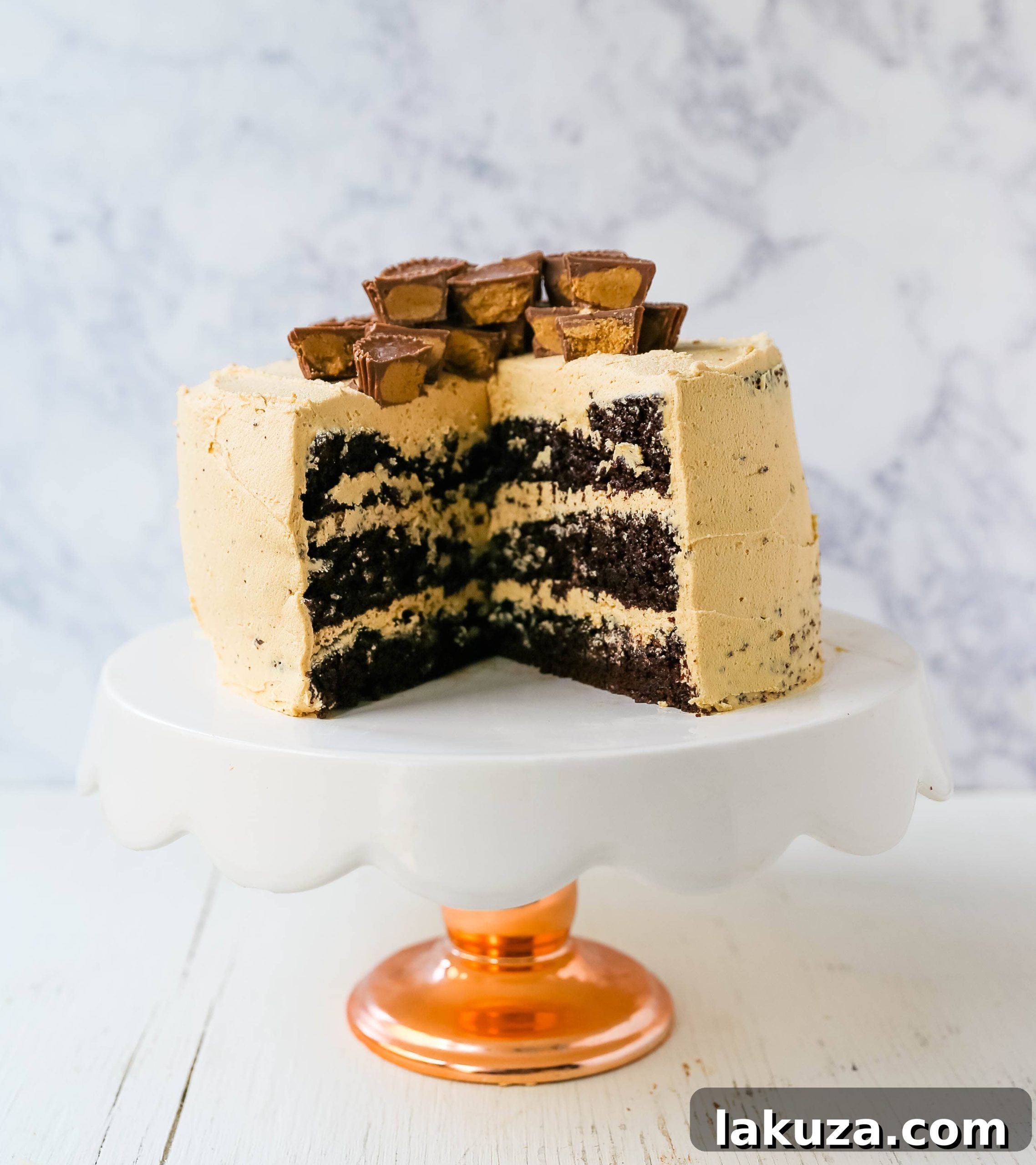 A baker's perspective on frosting a layer of the chocolate cake with peanut butter frosting.