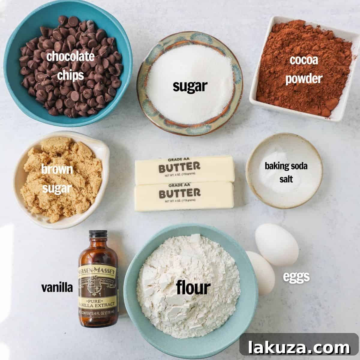 An array of ingredients laid out for making double chocolate chip cookies, including butter, sugars, eggs, vanilla, cocoa powder, flour, baking soda, salt, and various chocolate chips.