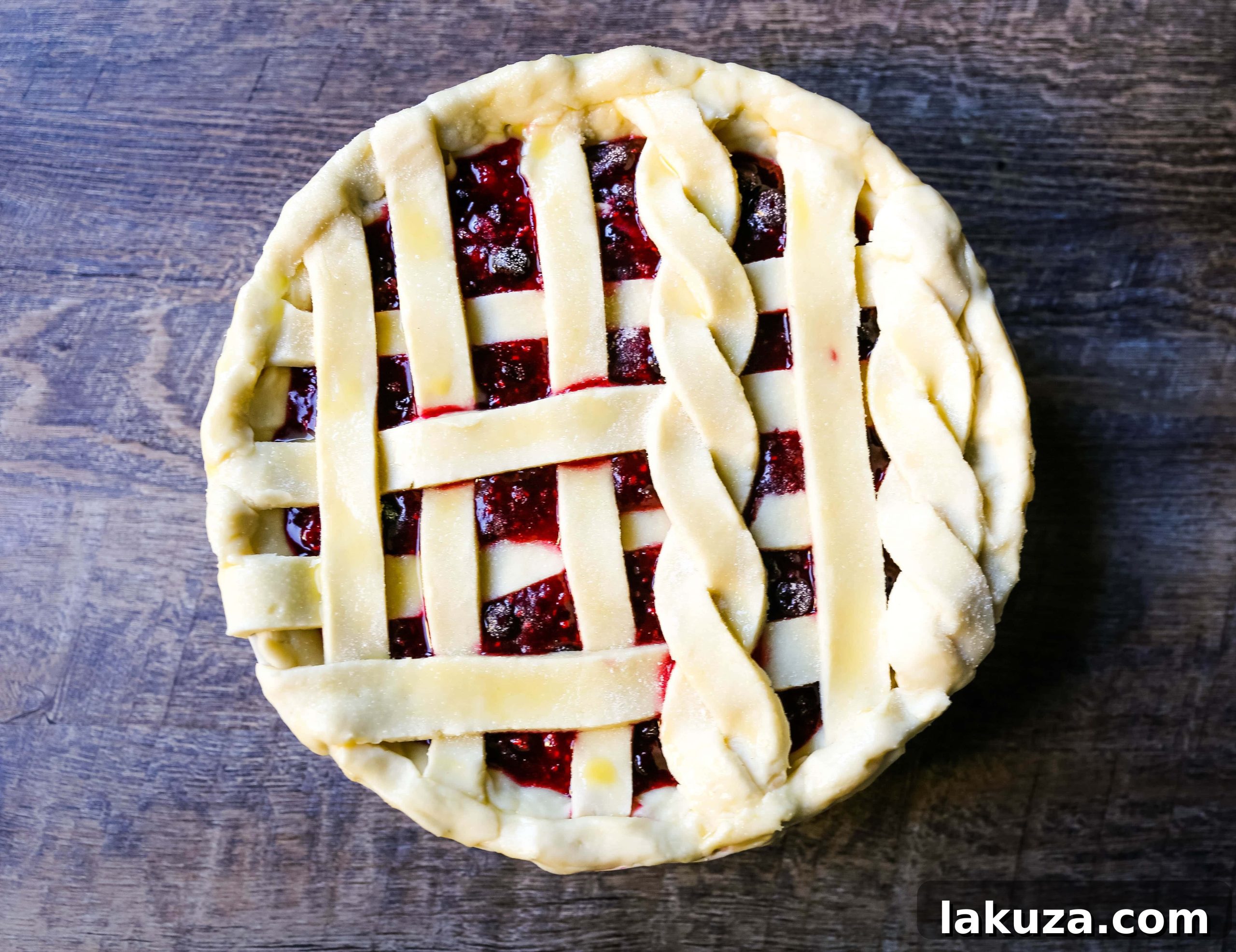 Berry Burst Pie 3 A close-up of a freshly baked Triple Berry Pie with a golden, crimped crust, showcasing the vibrant berry filling bubbling through the lattice top. A true masterpiece of homemade dessert baking.