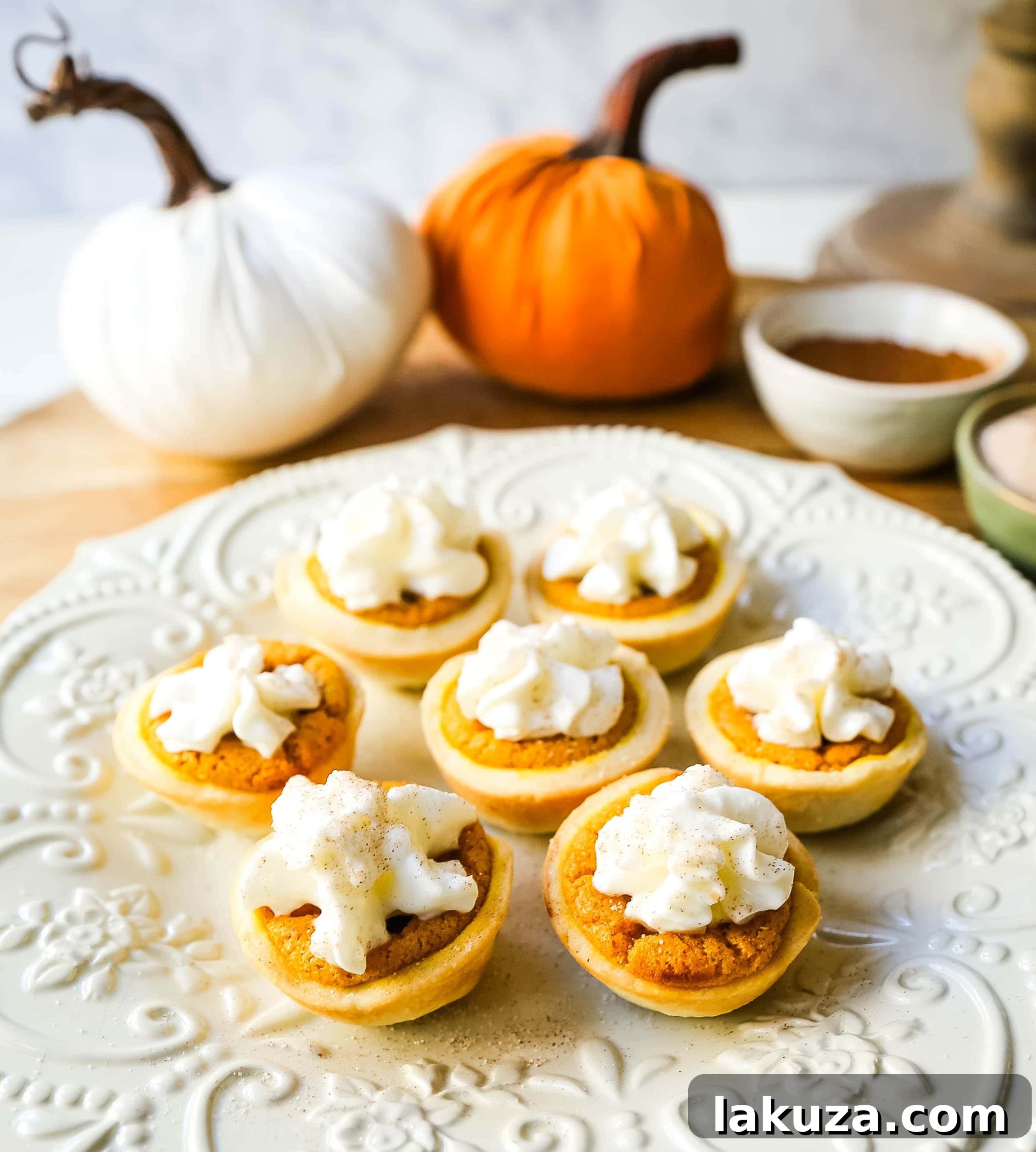 Pumpkin Pie Poppers 4 A festive platter of Mini Pumpkin Pie Bites, garnished with a swirl of fresh whipped cream, ready to serve at a holiday gathering.