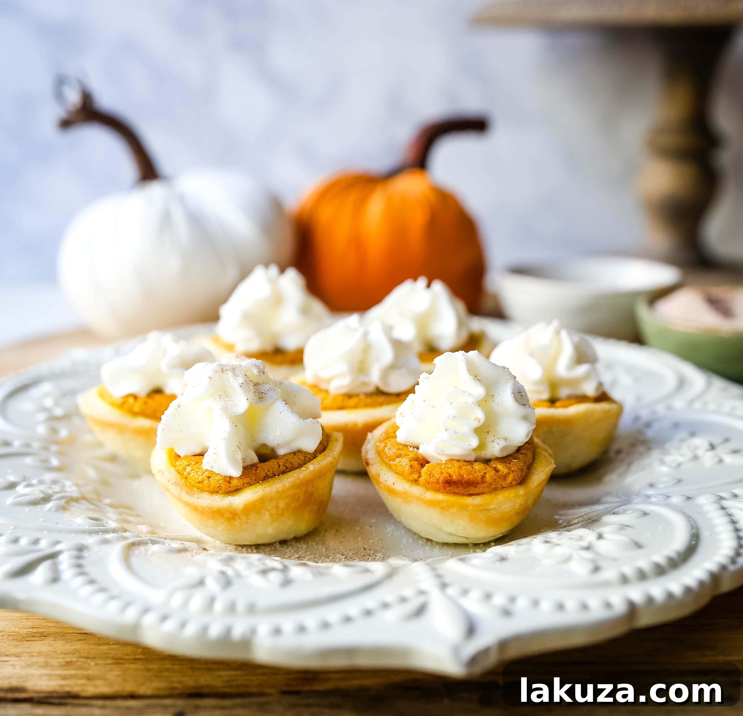 Pumpkin Pie Poppers 6 Preparation of Mini Pumpkin Pie Bites, with pumpkin filling being spooned into individual pie crusts in a mini muffin tin.