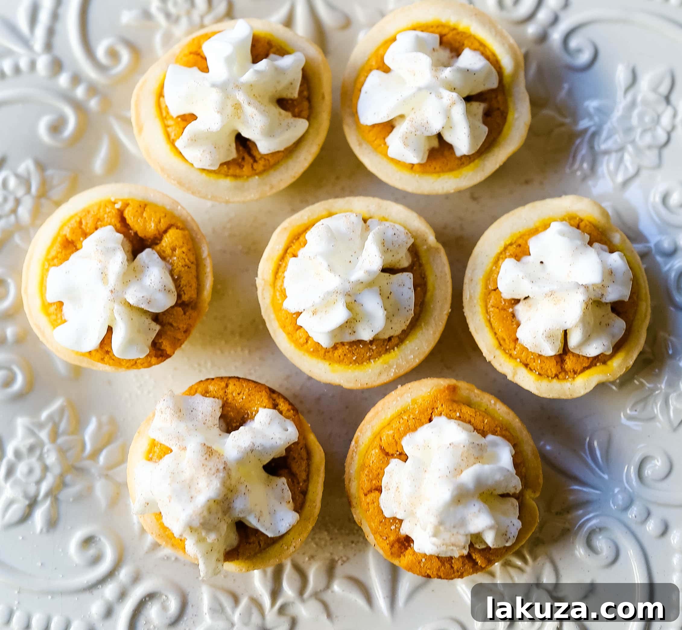 Pumpkin Pie Poppers 7 A finished Mini Pumpkin Pie Bite, beautifully topped with a swirl of homemade whipped cream, ready for a festive holiday table.
