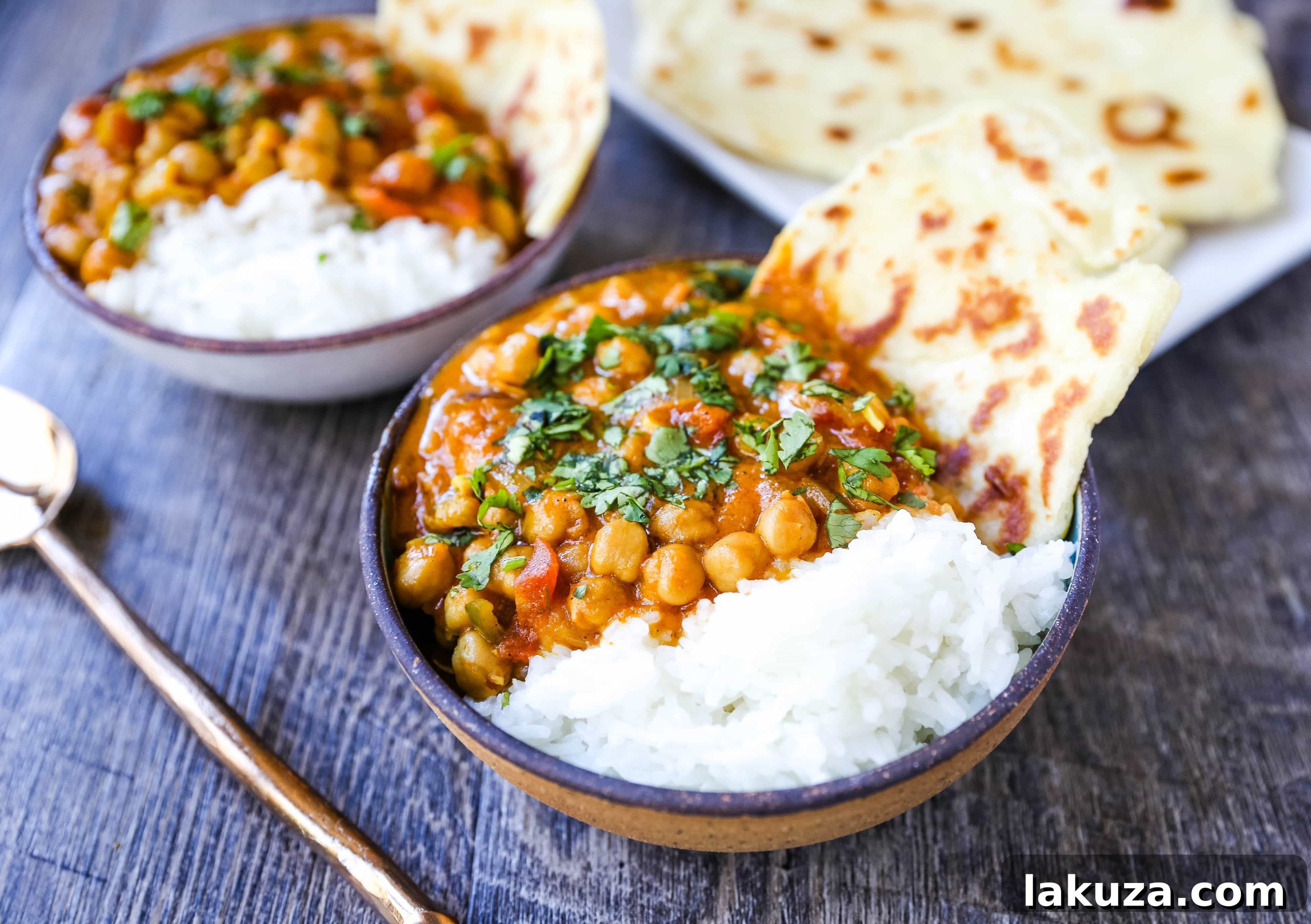 Close-up of Coconut Chickpea Curry simmering in a skillet, showcasing the rich, golden broth and plump chickpeas.