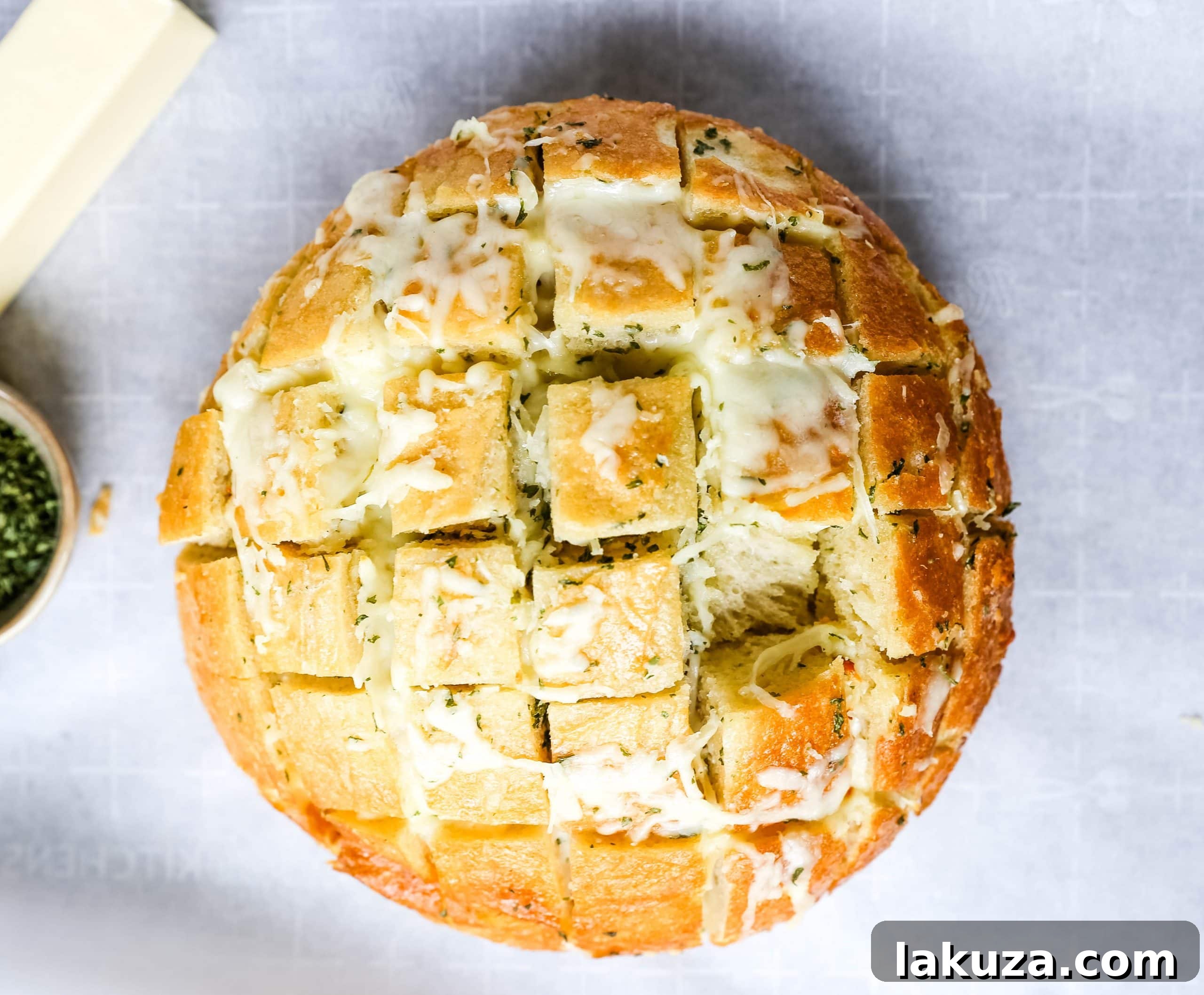 Overhead view of a baked cheesy garlic bread, golden and ready to be pulled apart, with wisps of steam