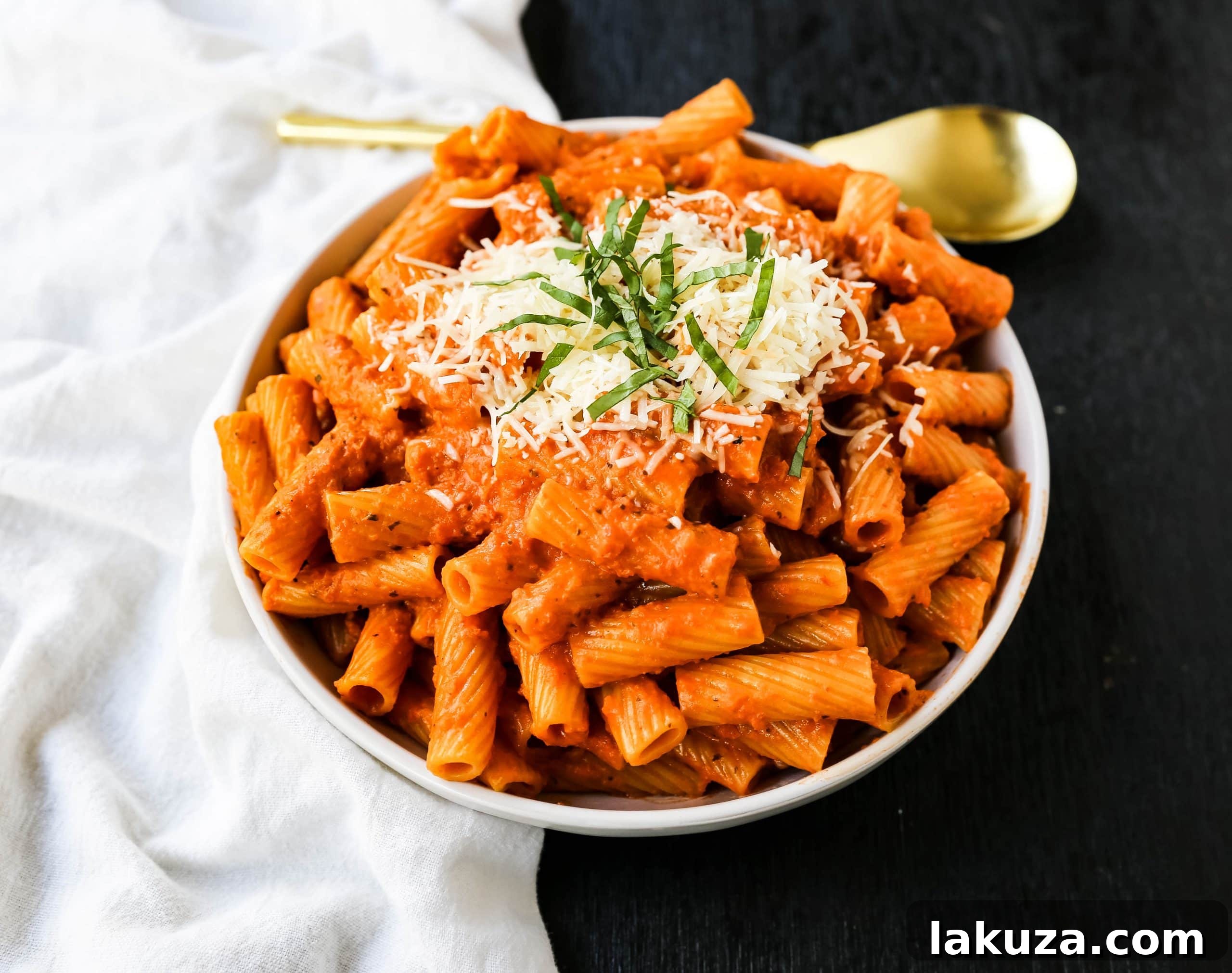 Close-up of Creamy Roasted Red Pepper Pasta, garnished with fresh basil and Parmesan.