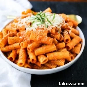 Creamy Roasted Red Pepper Pasta - A creamy roasted red pepper and tomato basil sauce with garlic and heavy cream all tossed together with pasta and topped with parmesan cheese.