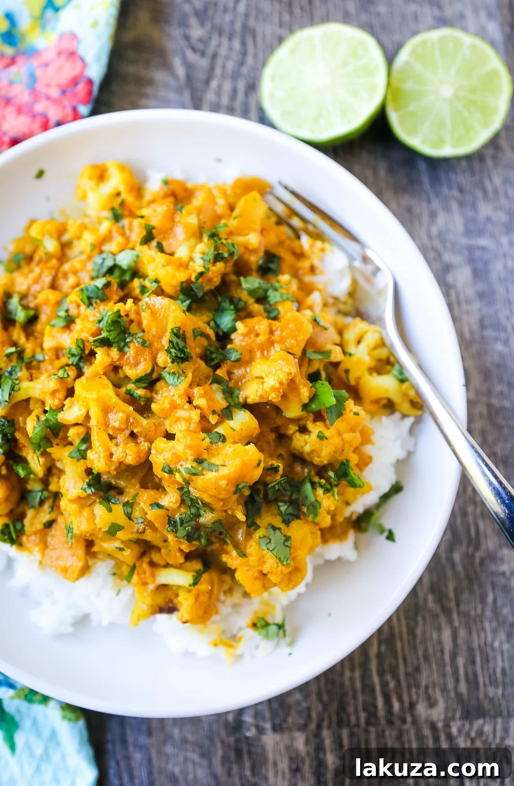 A vibrant bowl of Coconut Cauliflower Curry served with fluffy rice and fresh lime wedges.