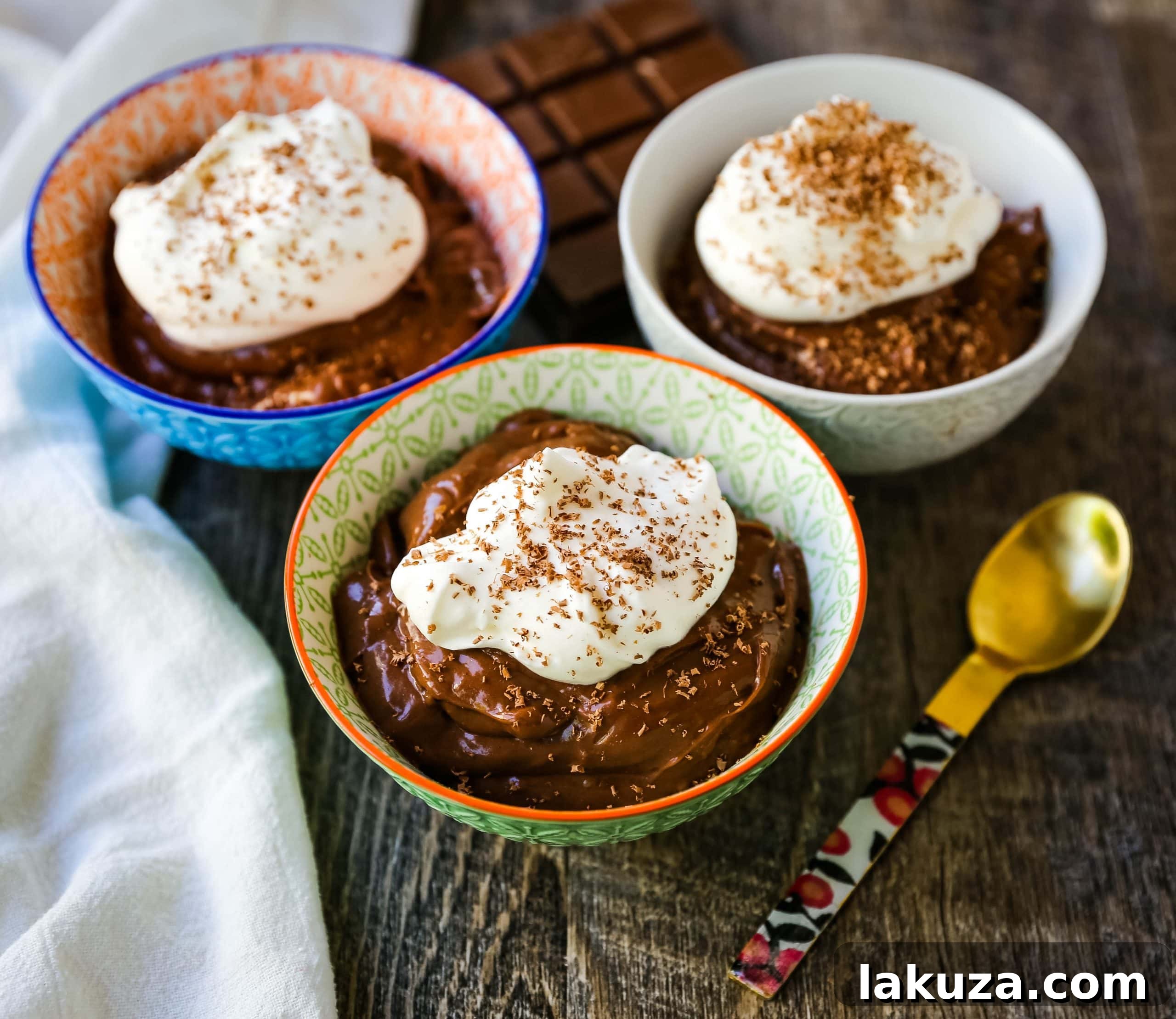 A bowl of freshly made chocolate pudding, topped with a dollop of whipped cream and delicate chocolate shavings, ready to be served.