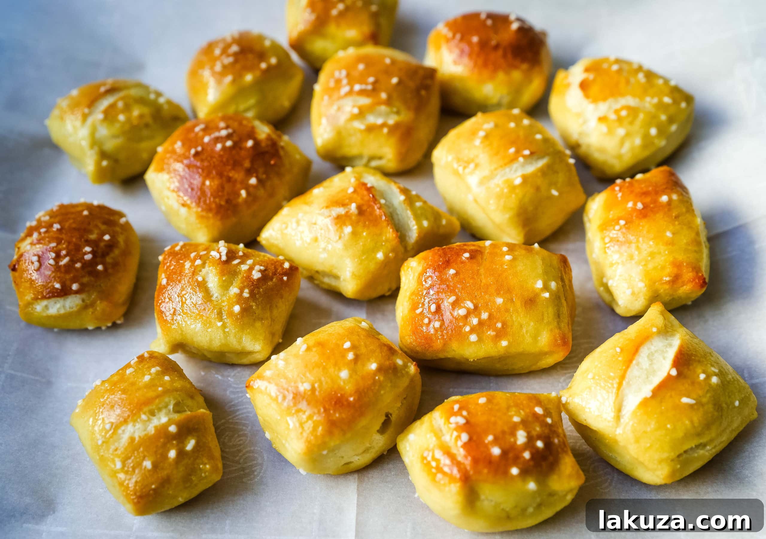 A tray filled with golden-brown homemade pretzel bites, some seasoned with coarse salt, others plain, highlighting their soft texture.
