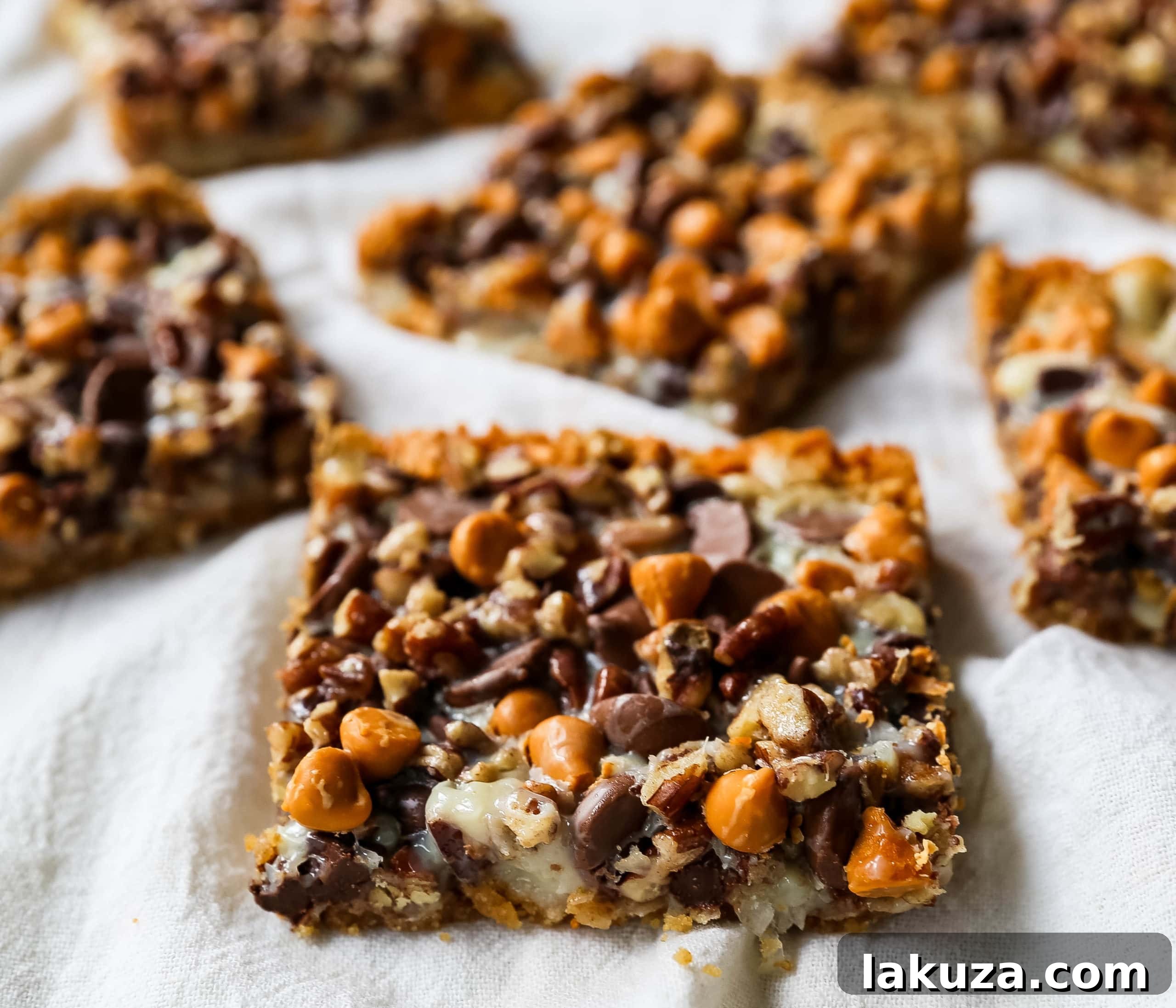 Decadent Seven-Layer Dream Bars 5 Individual 7-Layer Magic Bars arranged on a plate, showcasing their inviting golden color and loaded toppings.