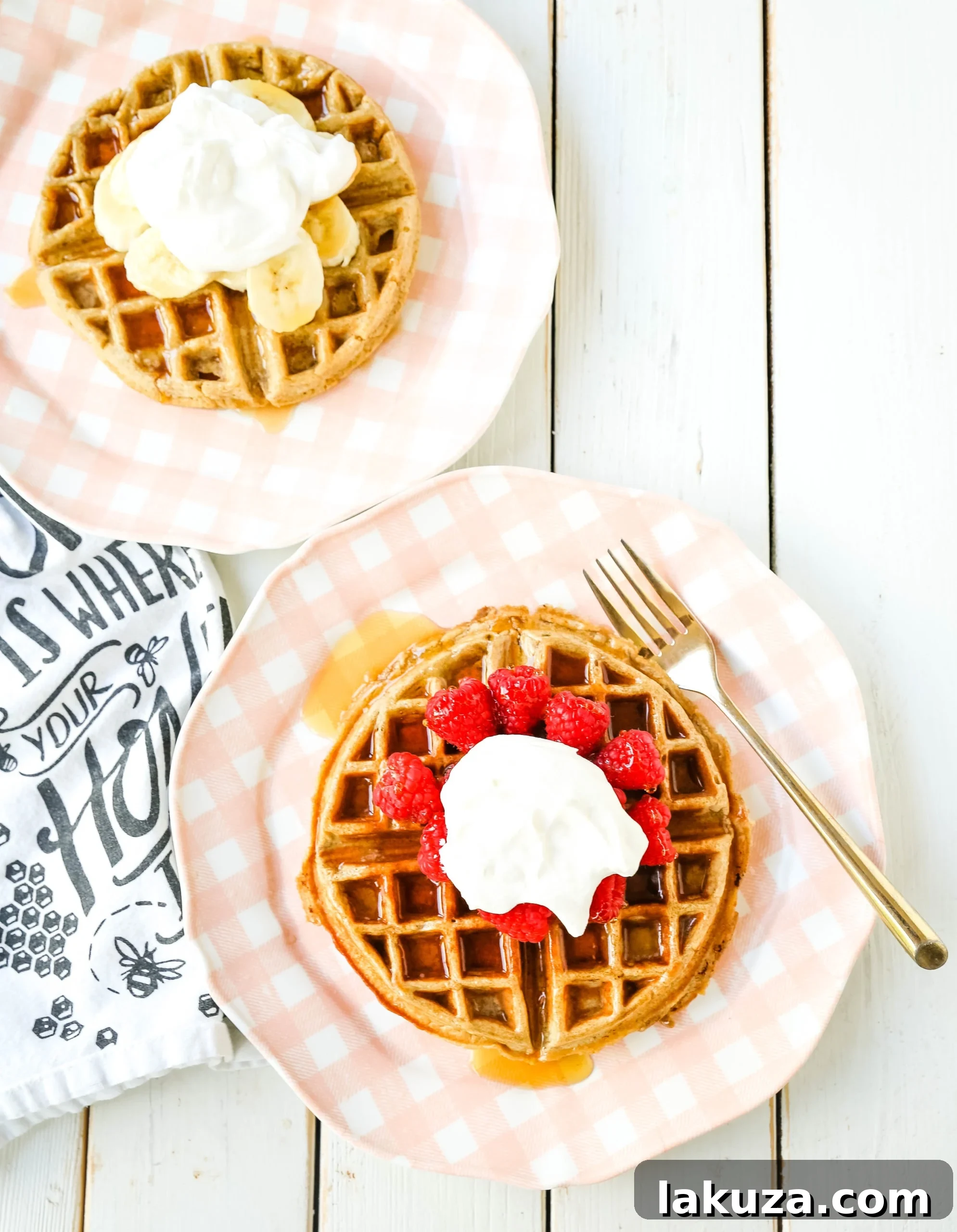 A hand drizzling pure maple syrup over a plate of healthy banana oat waffles with fresh berries