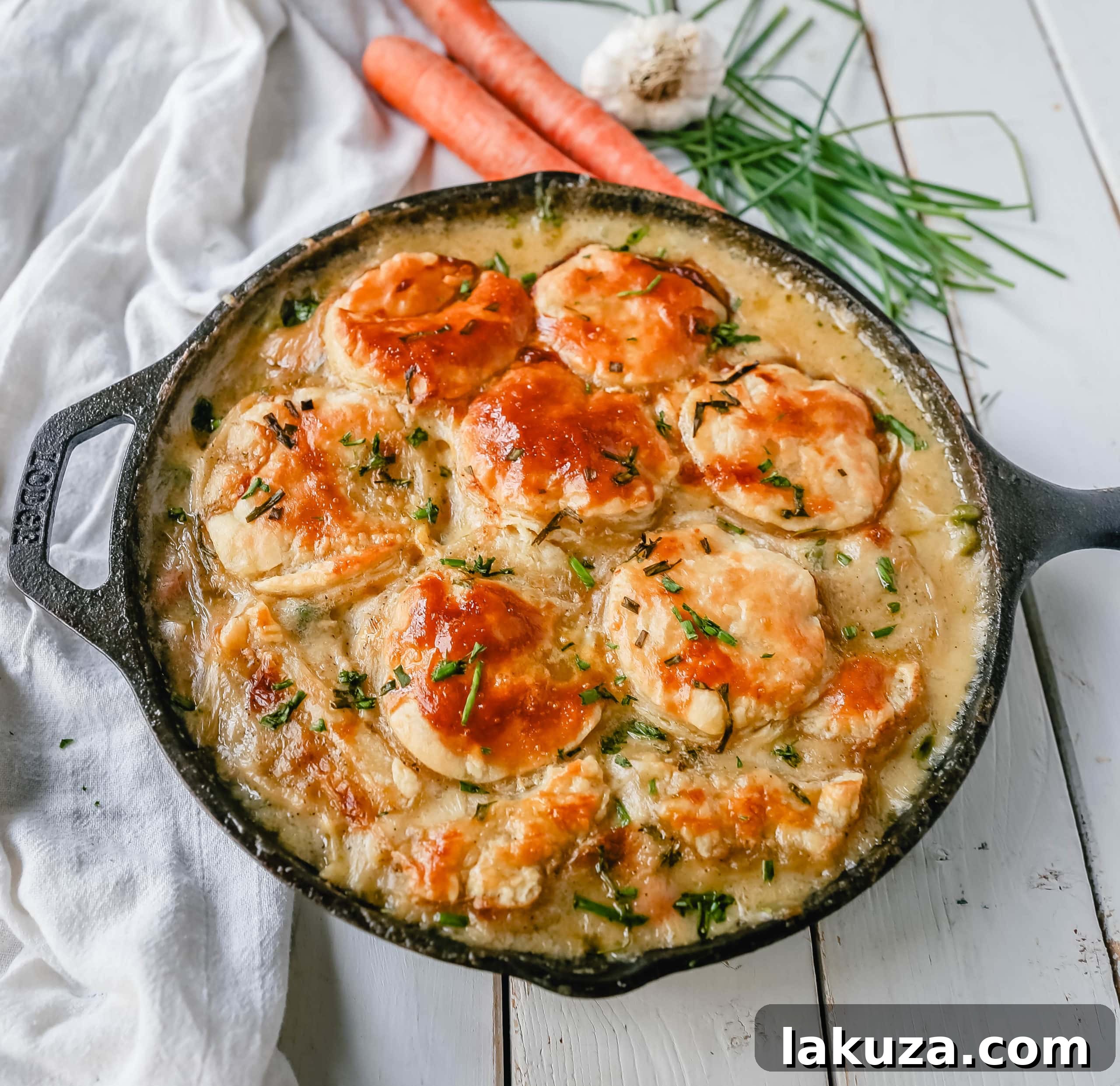 One-Skillet Chicken Pot Pie cooking in a cast iron pan, showing the rich, creamy filling with chicken, carrots, and peas before the puff pastry is added. A perfect homemade comfort meal made easy.