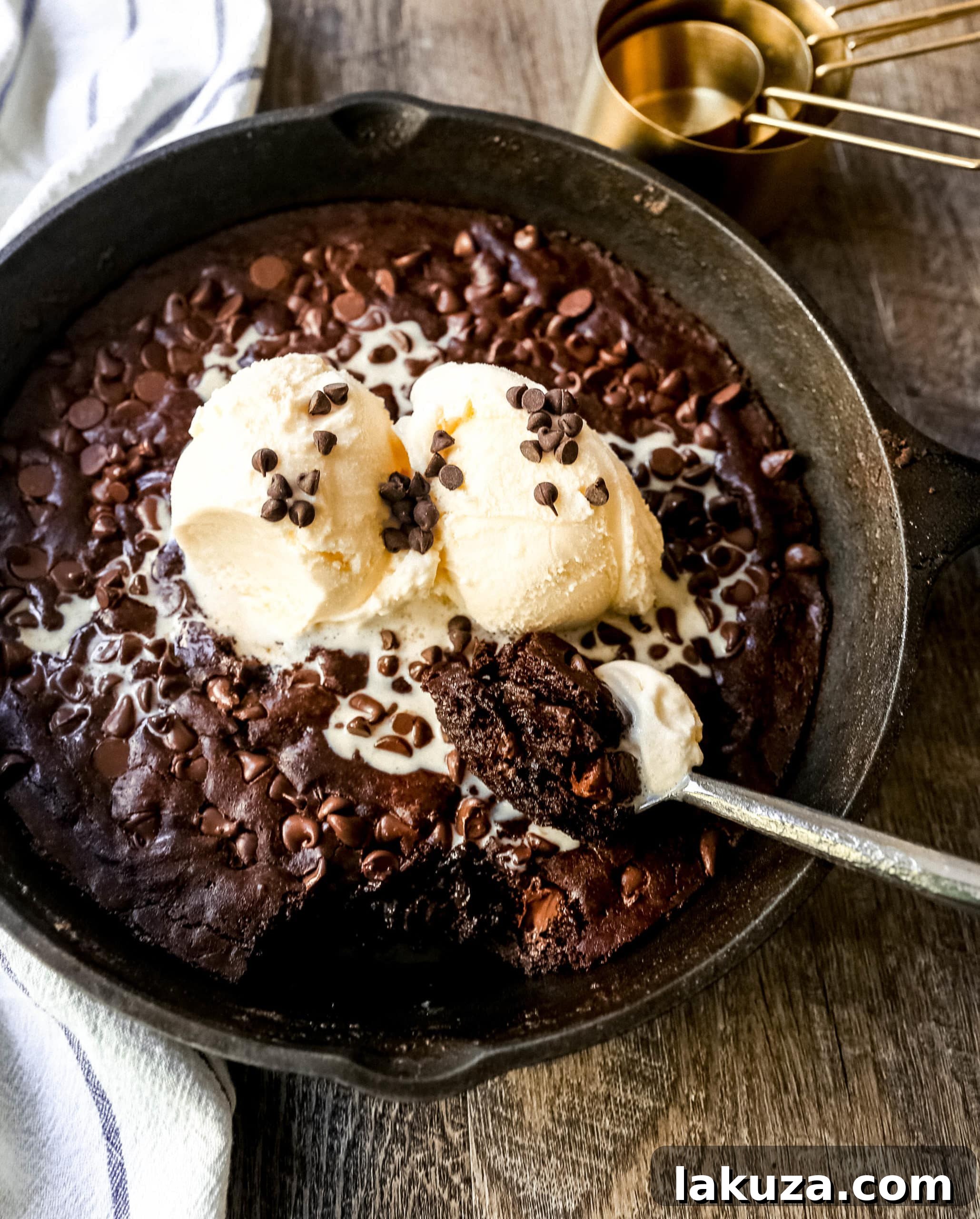 Warm Double Chocolate Chip Skillet Cookie topped with melting vanilla ice cream and hot fudge, perfect for chocolate lovers.