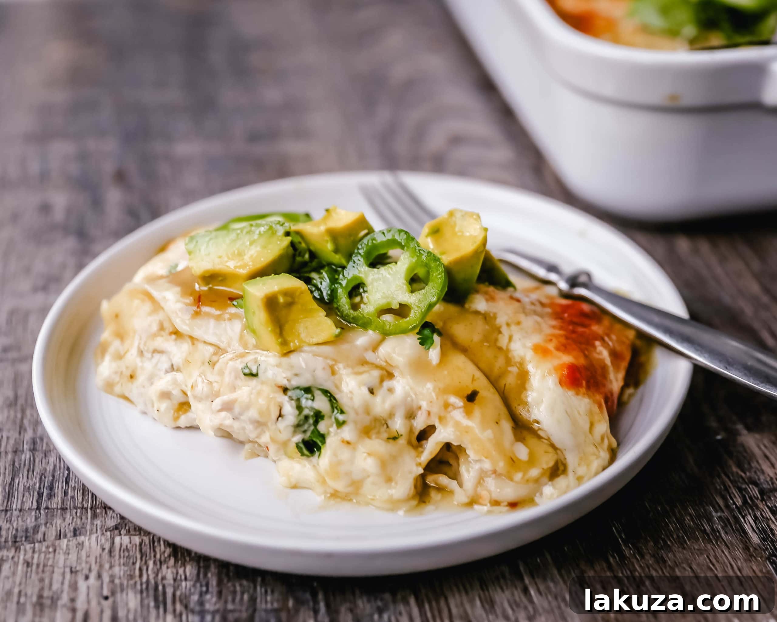 Velvety Green Chile Chicken Enchiladas 5 Assembled and unbaked creamy green chile chicken enchiladas in a baking dish, generously topped with shredded pepper jack cheese, ready for the oven.