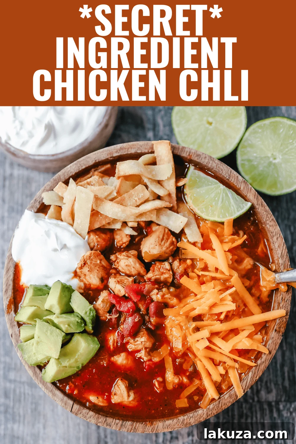 A bowl of homemade chicken chili with a generous topping of shredded Mexican cheese, fresh cilantro, and a dollop of sour cream. The chili is rich with Mexican spices, green chilies, and tender chicken, making it the perfect comforting meal. Recipe by Modern Honey. #chickenchili #comfortfood #chiliwithtoppings