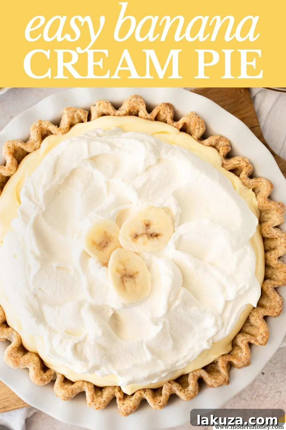 A stunning homemade banana cream pie, featuring a golden, flaky crust, layers of creamy vanilla pudding, fresh banana slices, and a cloud of whipped cream.
