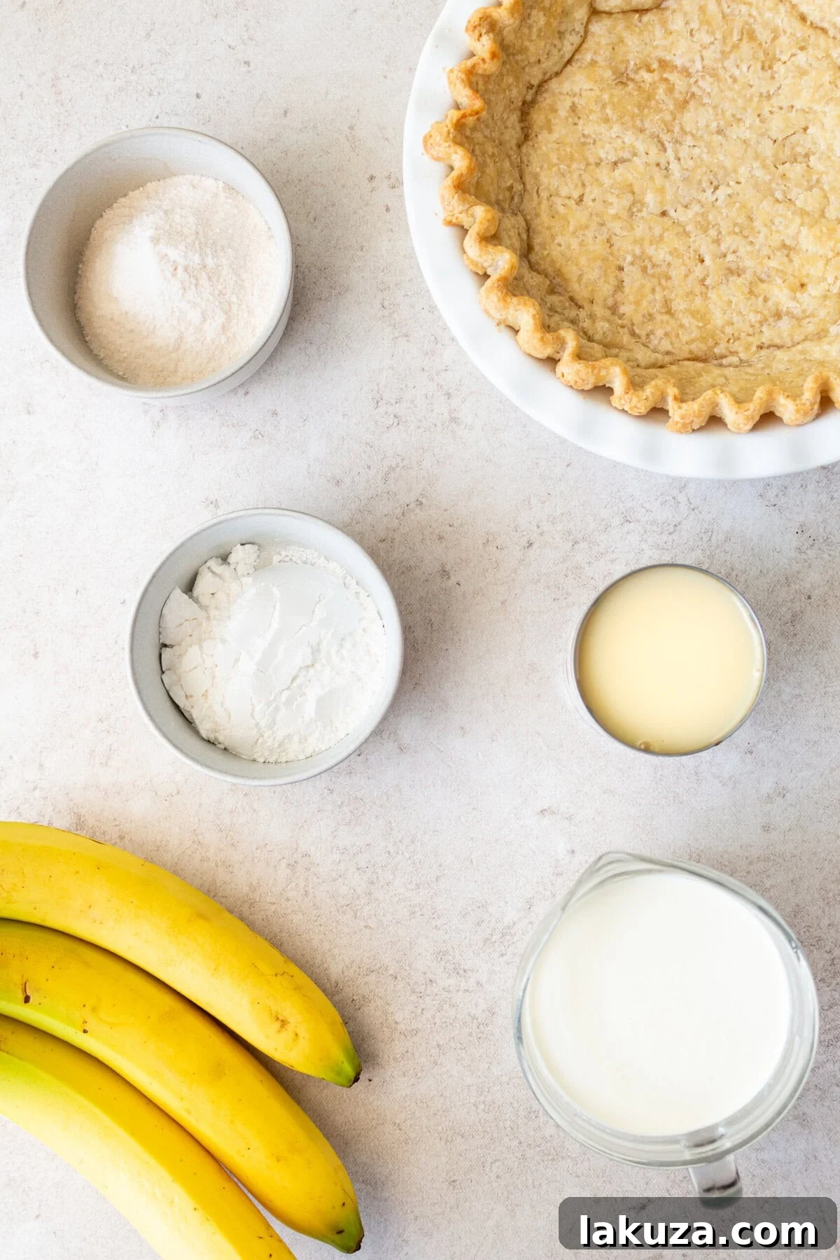 Essential ingredients for an easy banana cream pie, including instant vanilla pudding mix, sweetened condensed milk, heavy cream, fresh bananas, and pie crust ingredients.