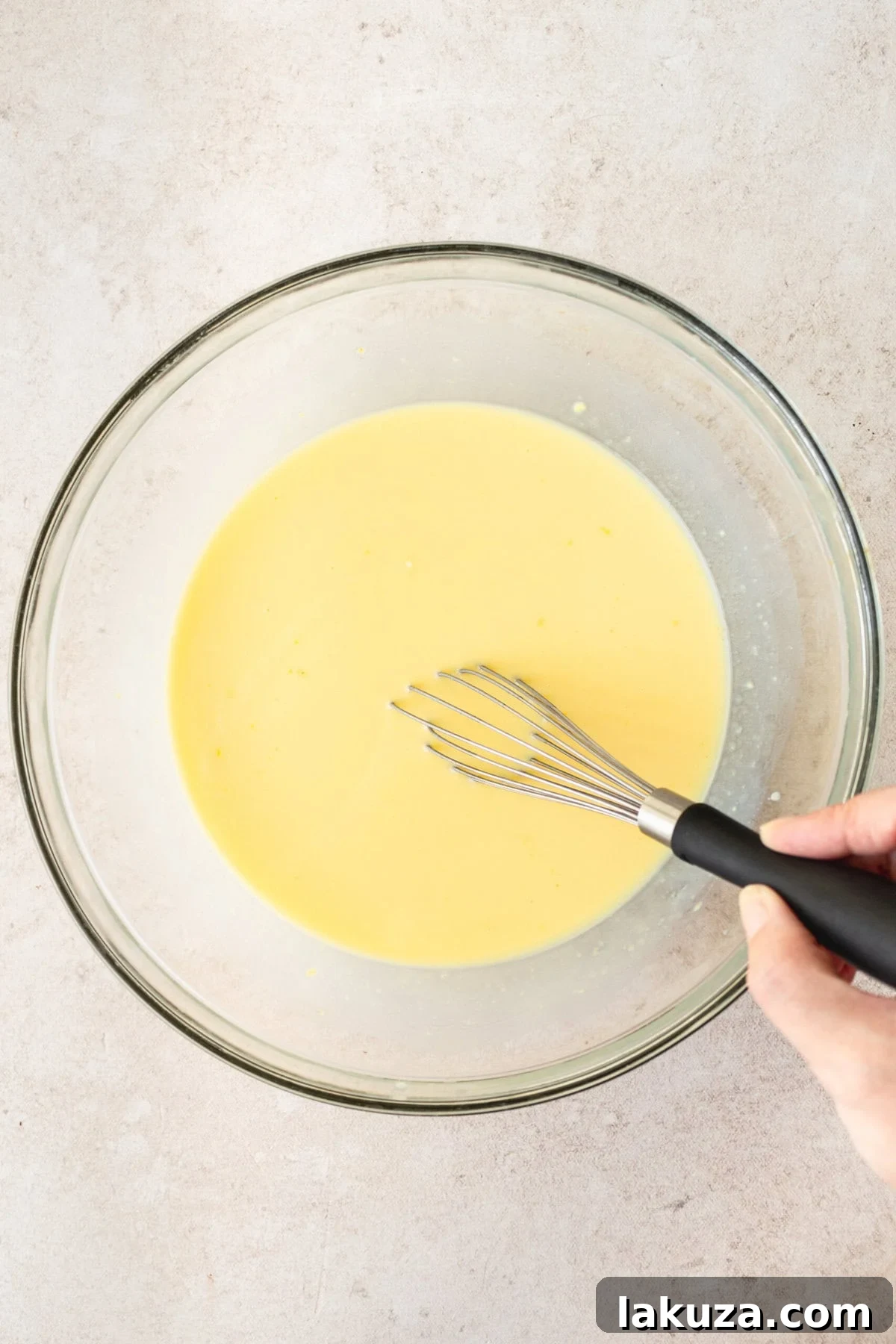 Mixing instant vanilla pudding mix, cold water, and sweetened condensed milk in a bowl with a whisk to create the banana cream pie filling base.
