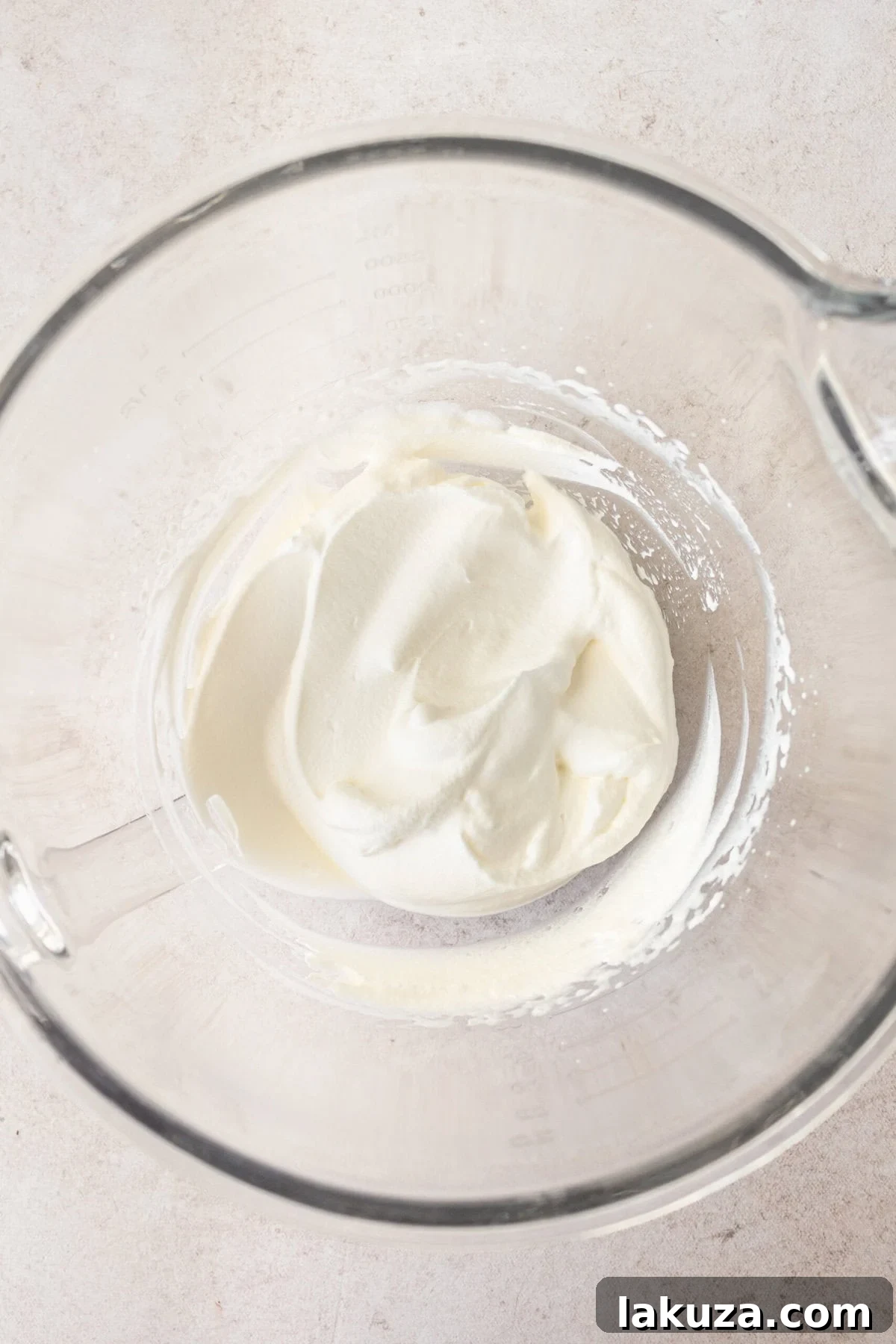 Freshly whipped heavy cream with soft peaks in a mixing bowl, ready to be folded into the vanilla pudding mixture.
