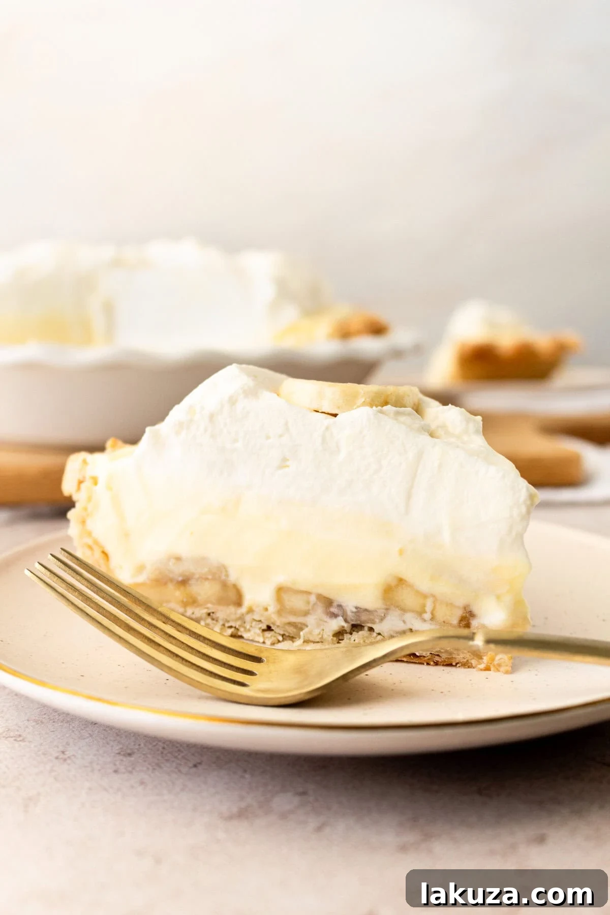 A delectable slice of homemade banana cream pie, showcasing its rich layers of buttery crust, creamy vanilla filling, and fresh bananas, topped with light whipped cream.