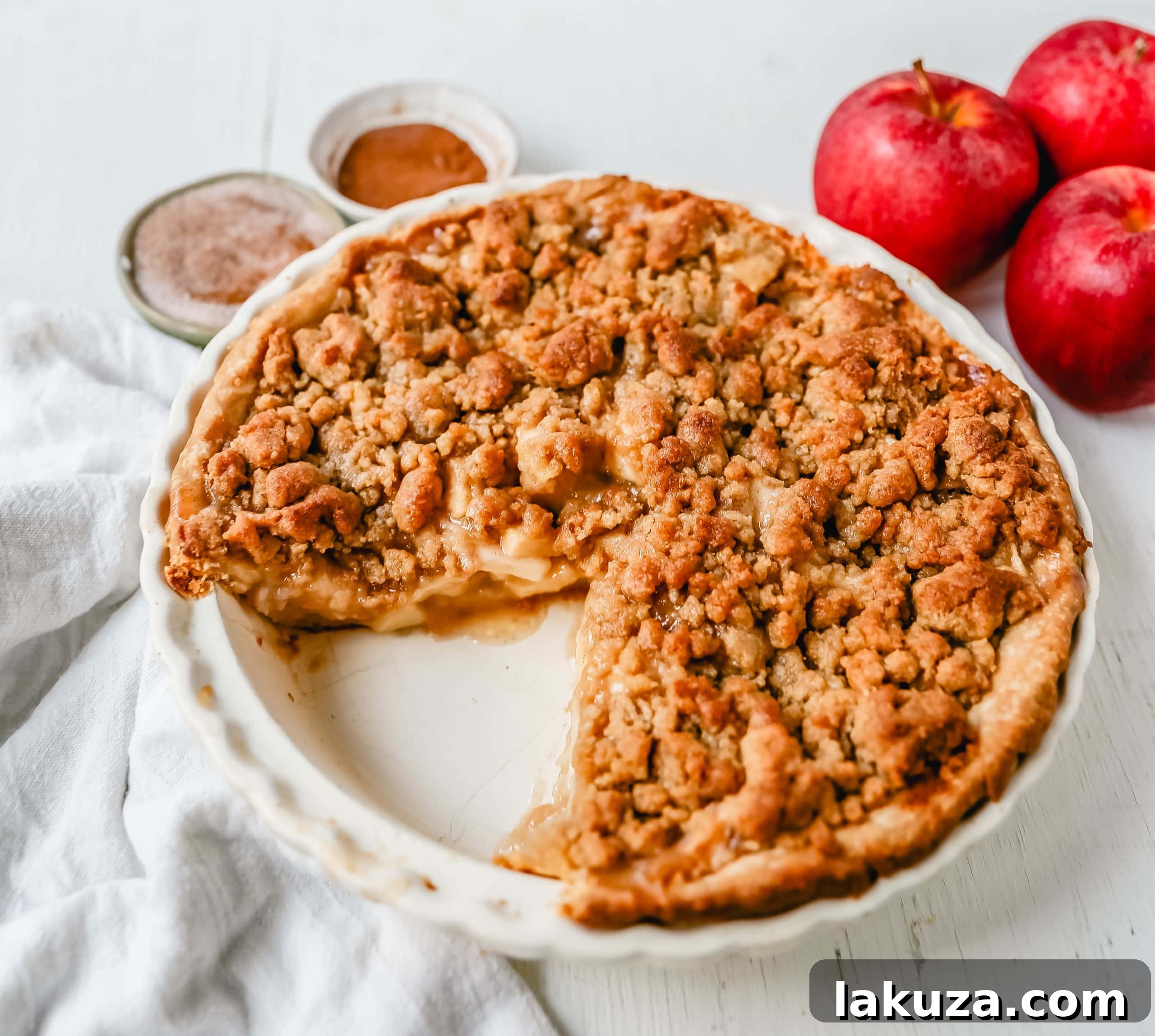 Authentic Dutch Apple Crumble 4 Slice of Dutch apple pie, revealing layers of spiced apples and the crumbly streusel topping, with a scoop of vanilla ice cream.