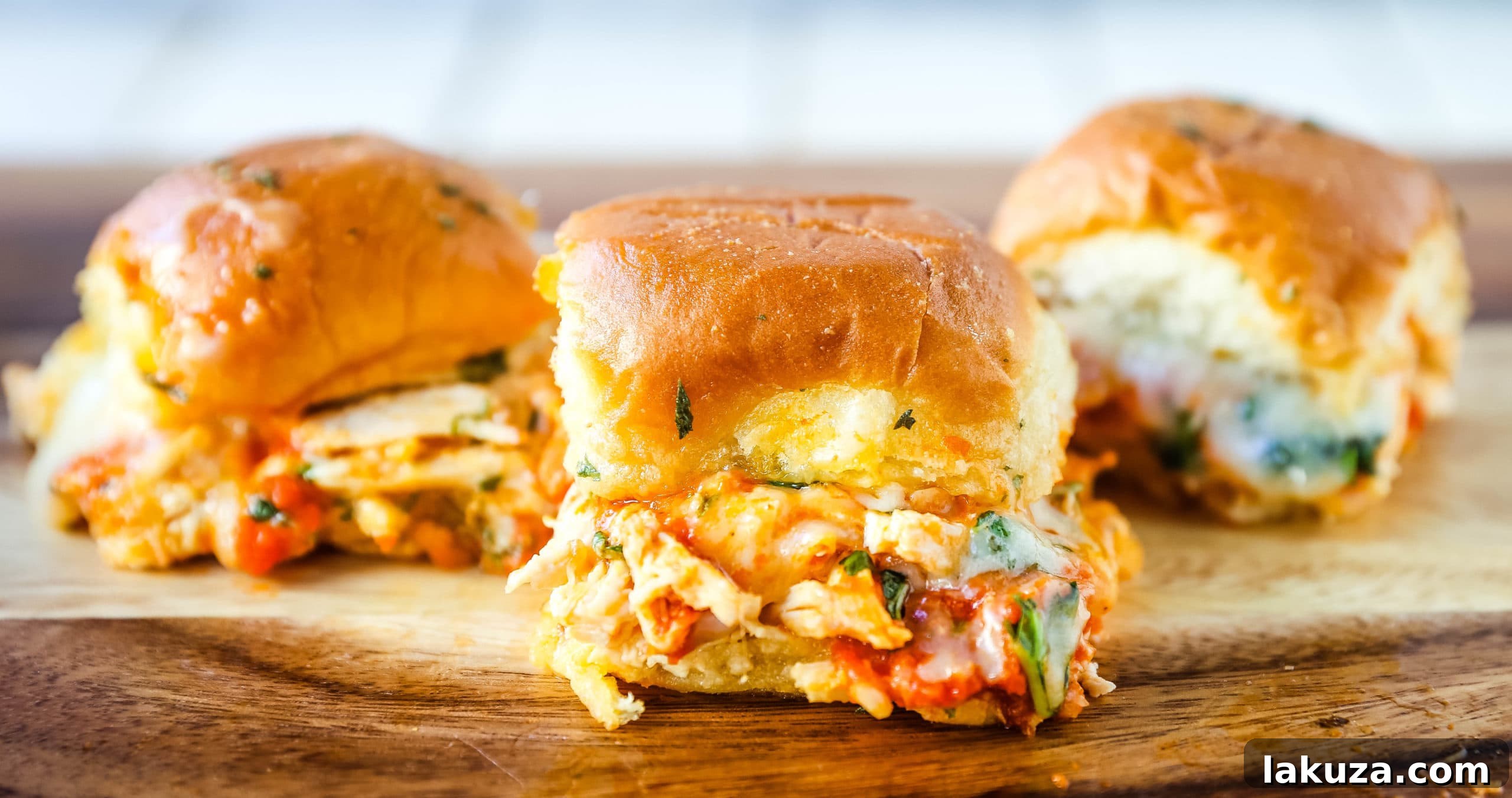 Close-up of golden-brown Baked Chicken Parm Sliders with bubbling cheese and fresh basil, ready to be served.