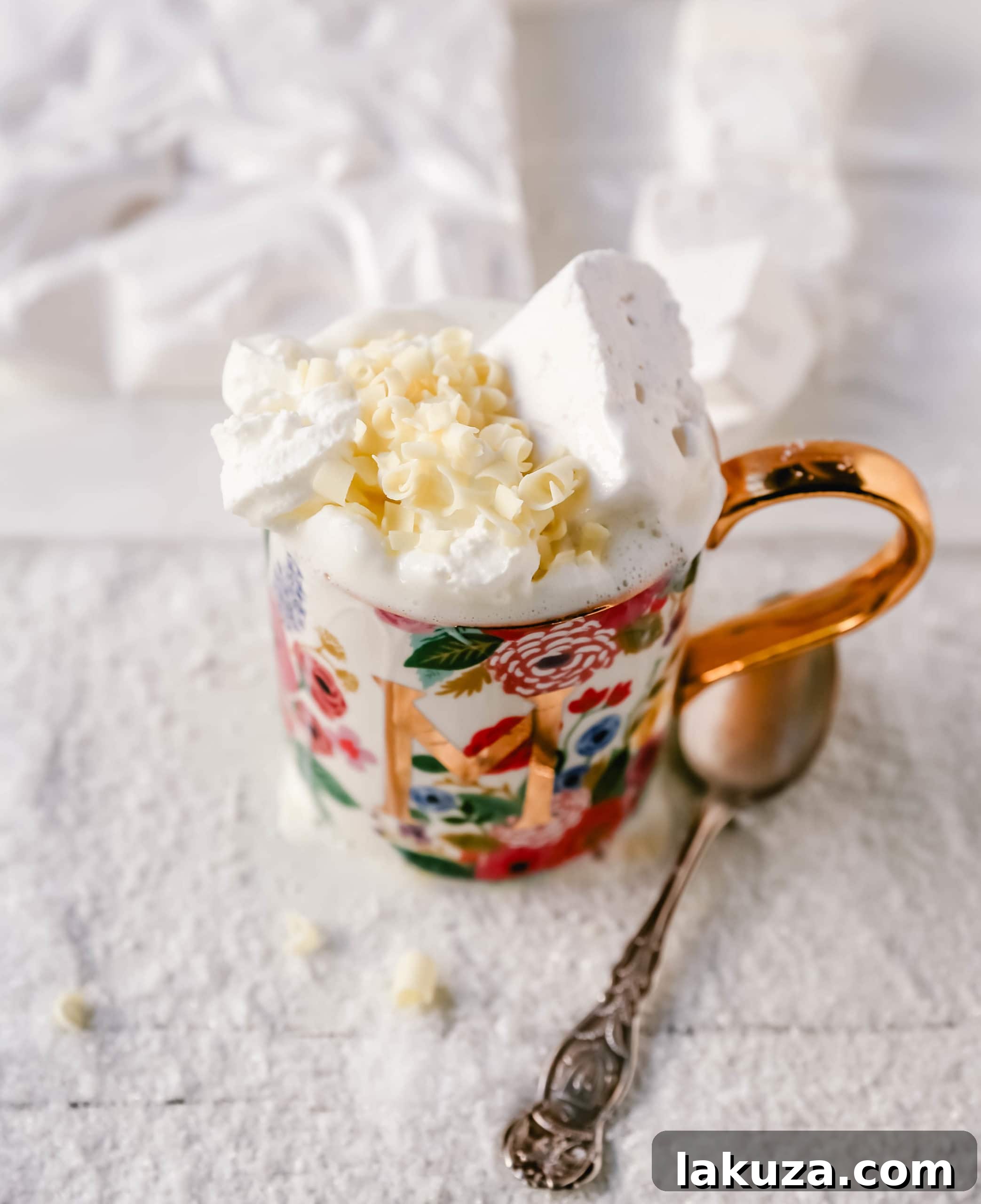 A festive red mug filled with homemade white hot chocolate, topped with whipped cream, mini marshmallows, and a sprinkle of cinnamon, ready to be enjoyed.
