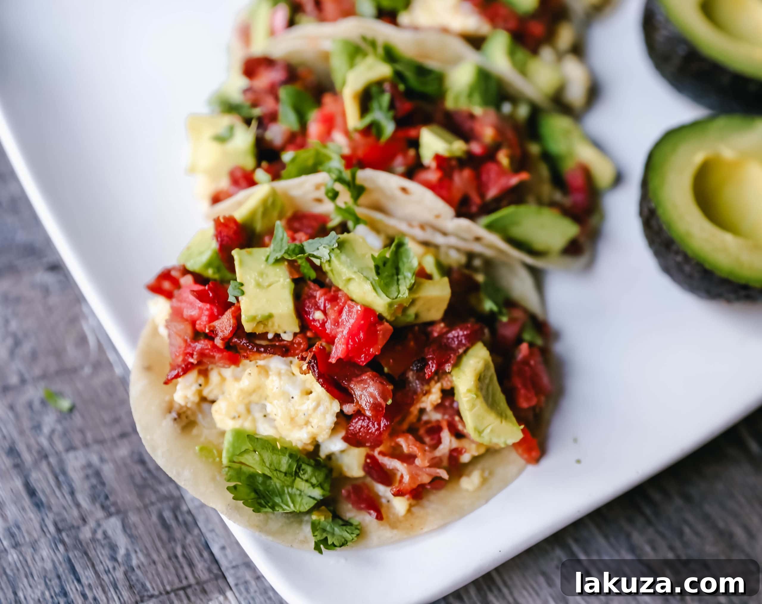 A close-up of a breakfast taco with bacon, egg, cheese, and avocado.