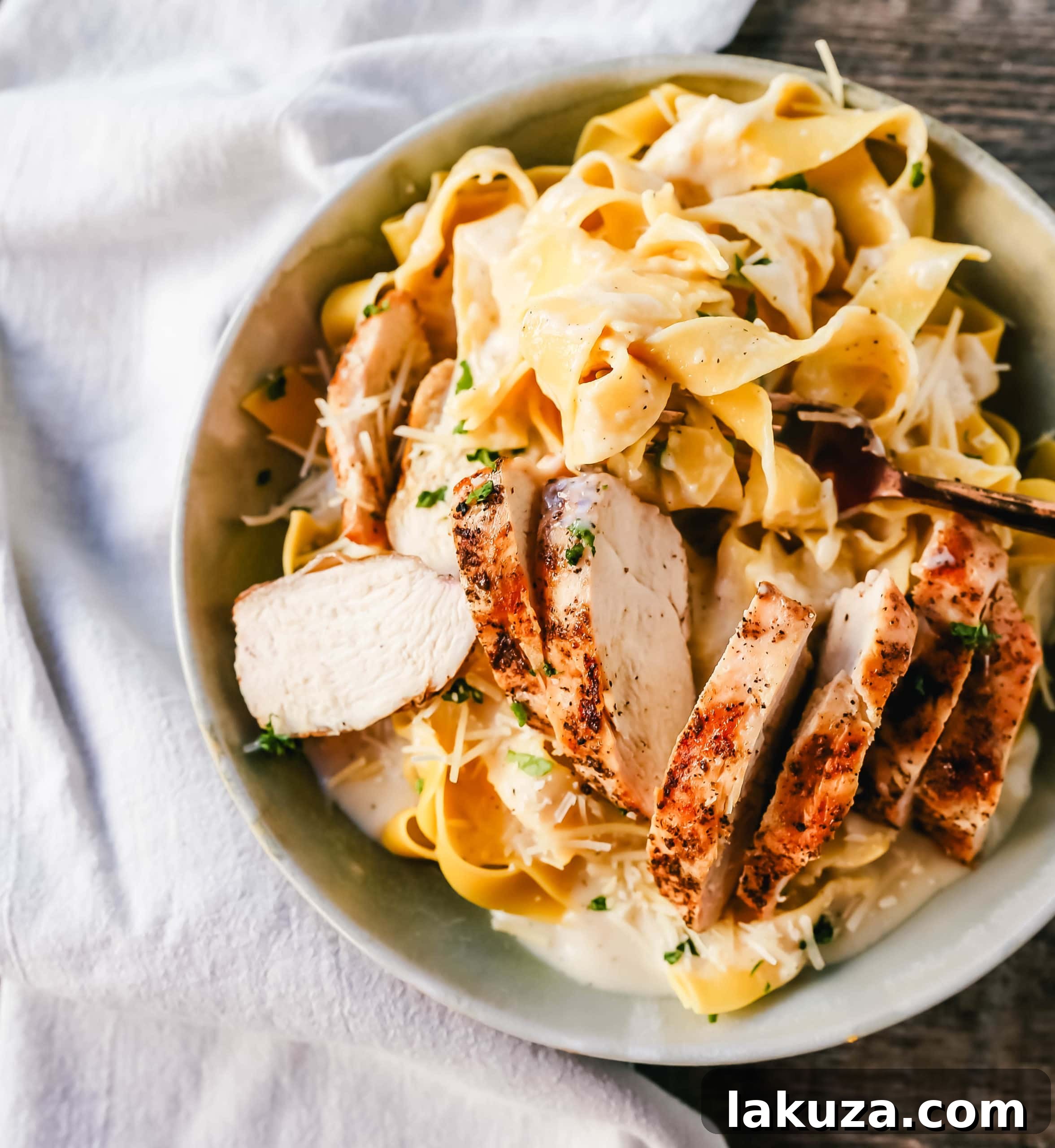 A serving of Skinny Low-Fat Chicken Fettuccine Alfredo, featuring tender grilled chicken and creamy low-fat alfredo sauce over fettuccine. A healthy and delicious meal. www.modernhoney.com #lowfat #chicken #pasta