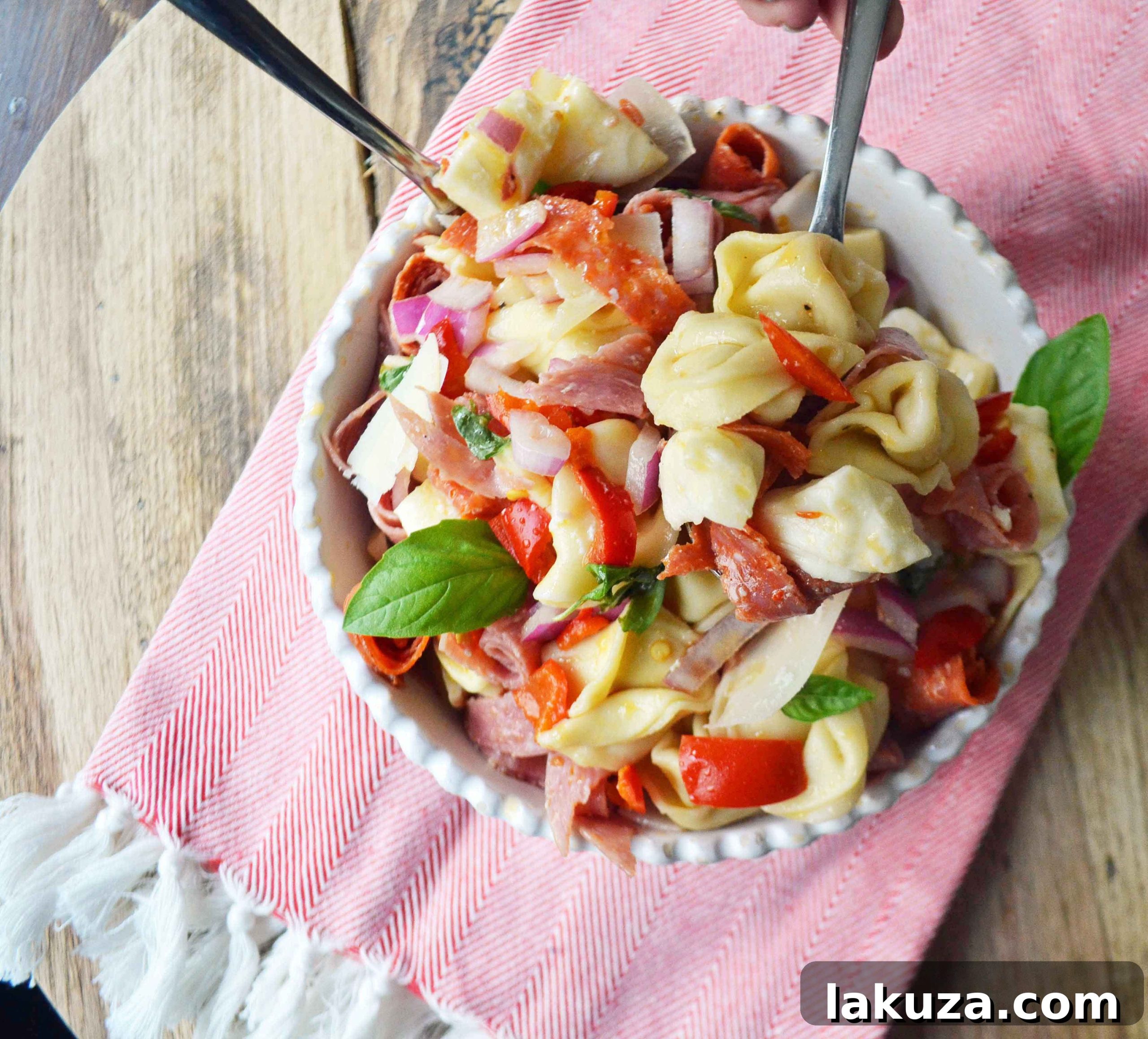 Close-up of a serving of Antipasto Tortellini Pasta Salad garnished with fresh basil