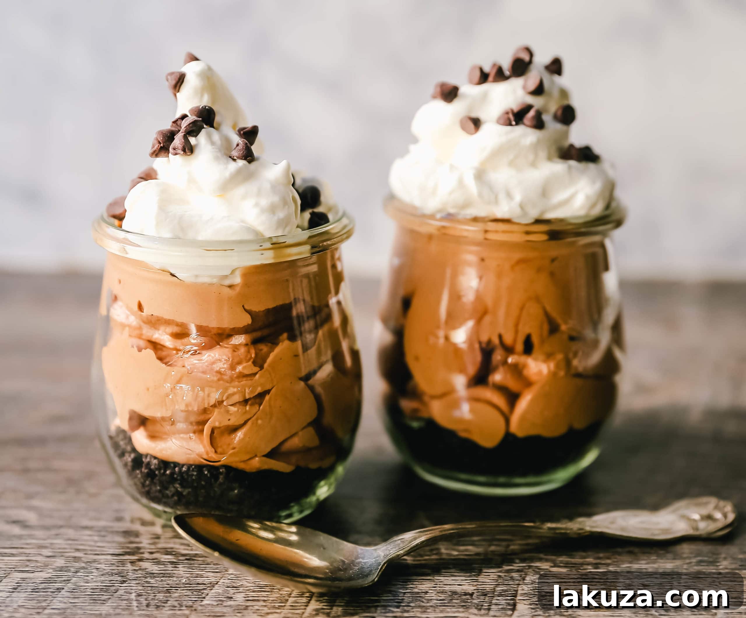 A close-up of a luscious Chocolate Nutella Cheesecake Mousse dessert in individual cups, layered with an OREO crust, creamy mousse, and topped with fresh whipped cream and chocolate curls. This easy, no-bake recipe features Nutella, cream cheese, heavy cream, and powdered sugar, making it perfect for quick celebrations. #nutellamousse #cheesecakedessert #easyrecipe #valentinesdessert