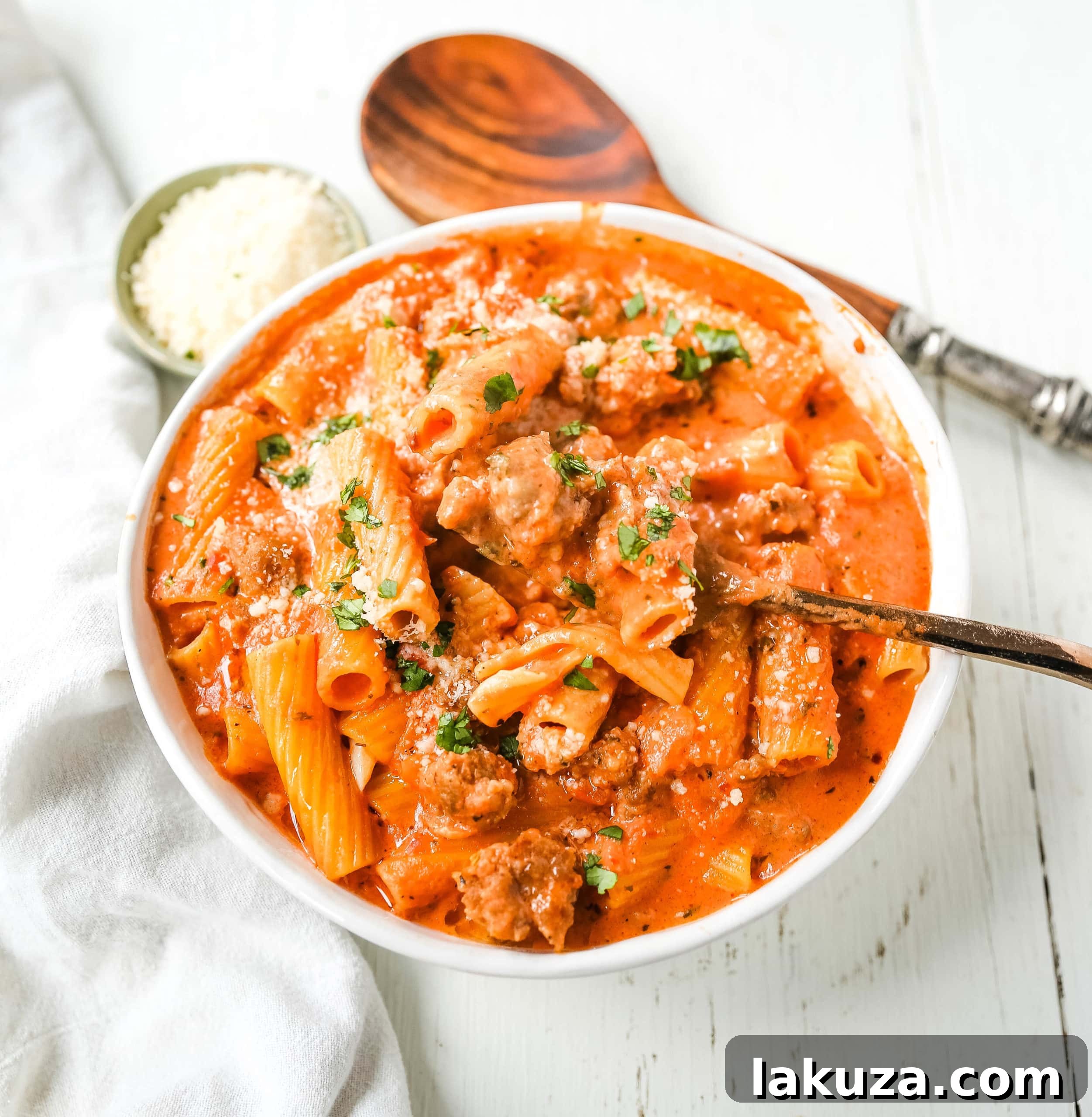 Close-up of creamy sausage rigatoni pasta garnished with fresh basil and Parmesan cheese.