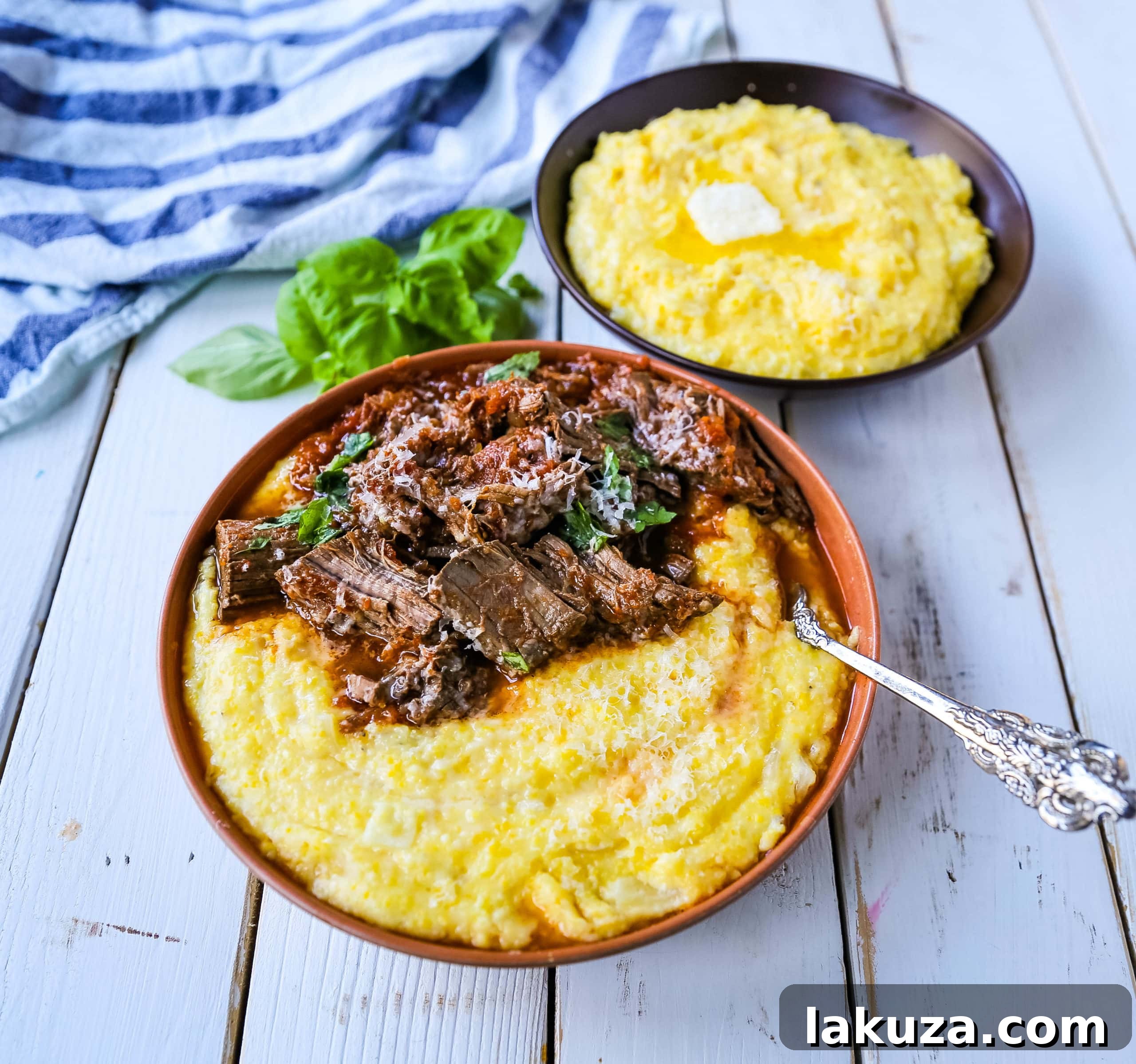 Slow-cooked Italian Braised Beef Ragu simmering in a cast iron pot with aromatic vegetables and herbs