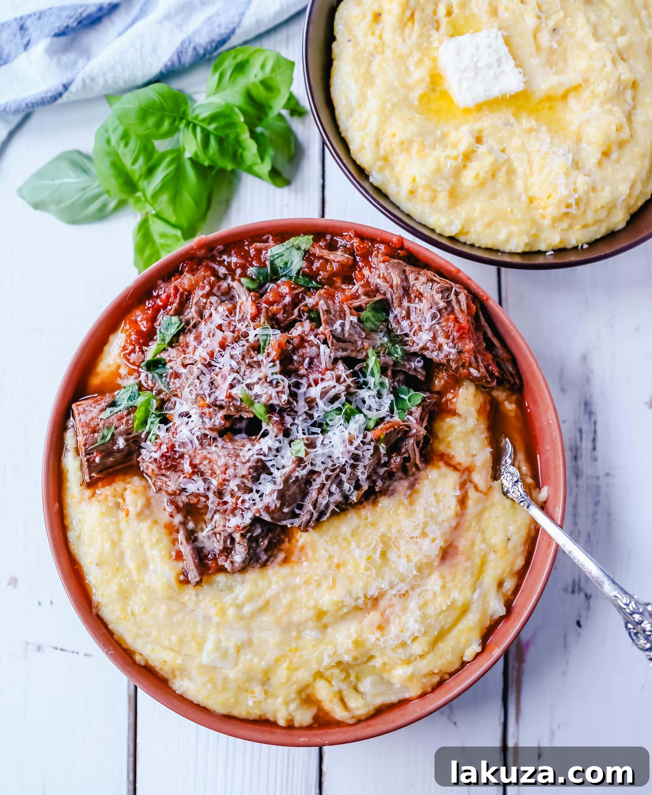 A close-up of tender shredded beef ragu served over creamy parmesan polenta in a white bowl