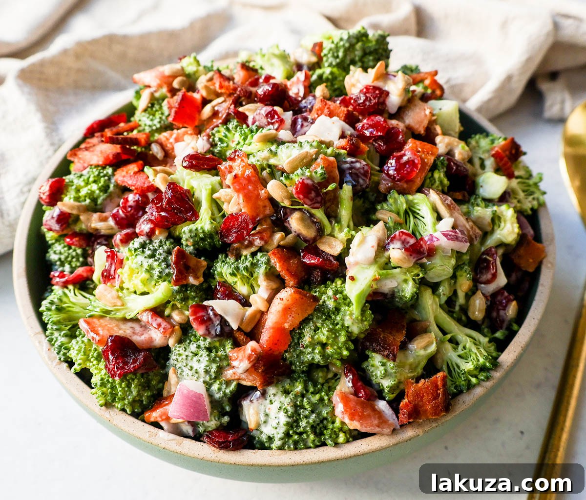 A bowl of homemade broccoli salad. Crunchy, easy broccoli salad with crispy bacon, sweet dried cranberries, onion, and nuts all tossed in a sweet and tangy dressing. Tips for making the best broccoli salad. A classic potluck, BBQ, or summer side dish recipe!