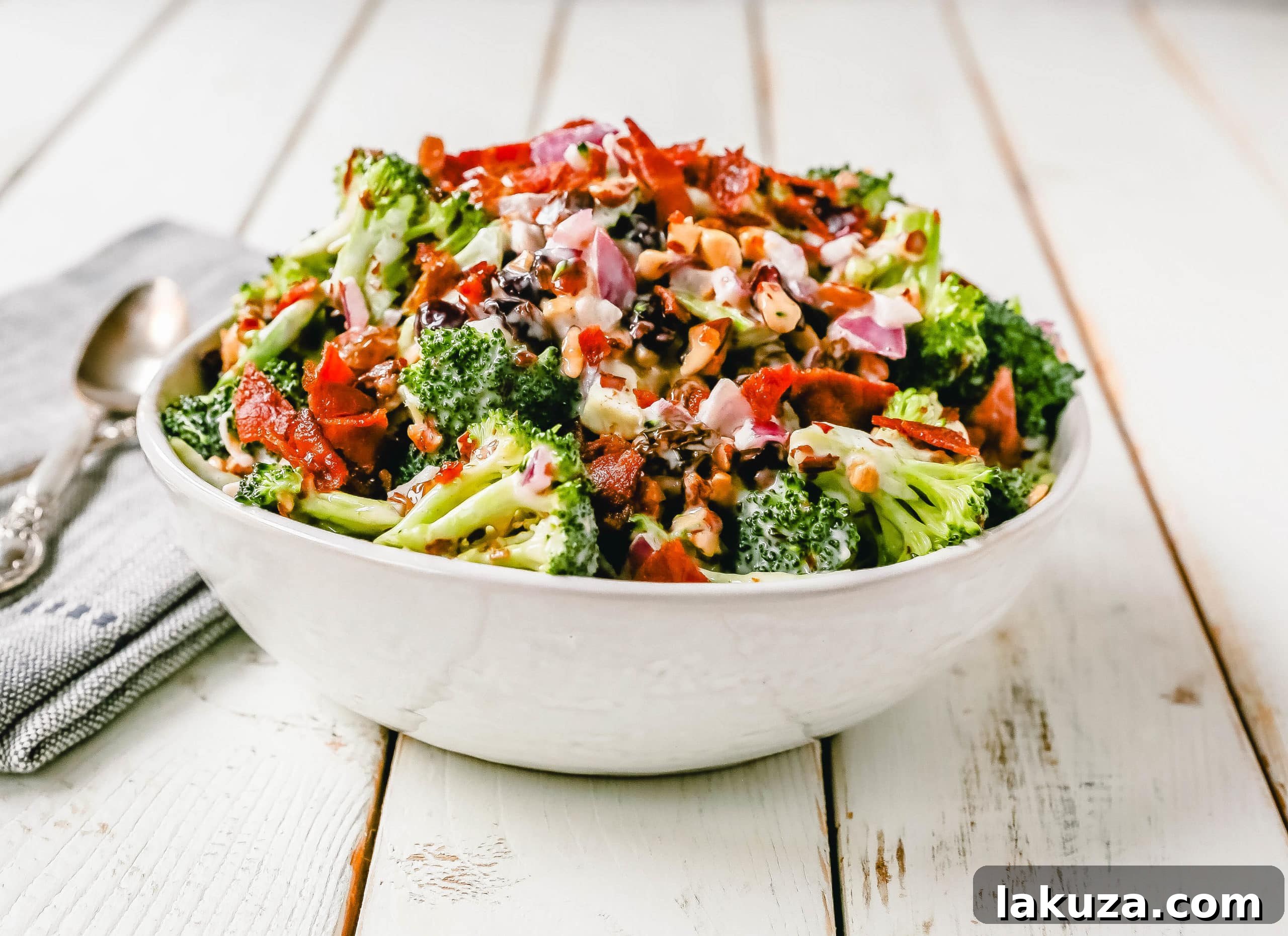 Broccoli Salad. Crunchy broccoli salad with crispy bacon, sweet dried cranberries, onion, nuts, tossed in a sweet and tangy dressing. A classic potluck side dish recipe! www.modernhoney.com #broccolisalad #sidedish #potluck #sides