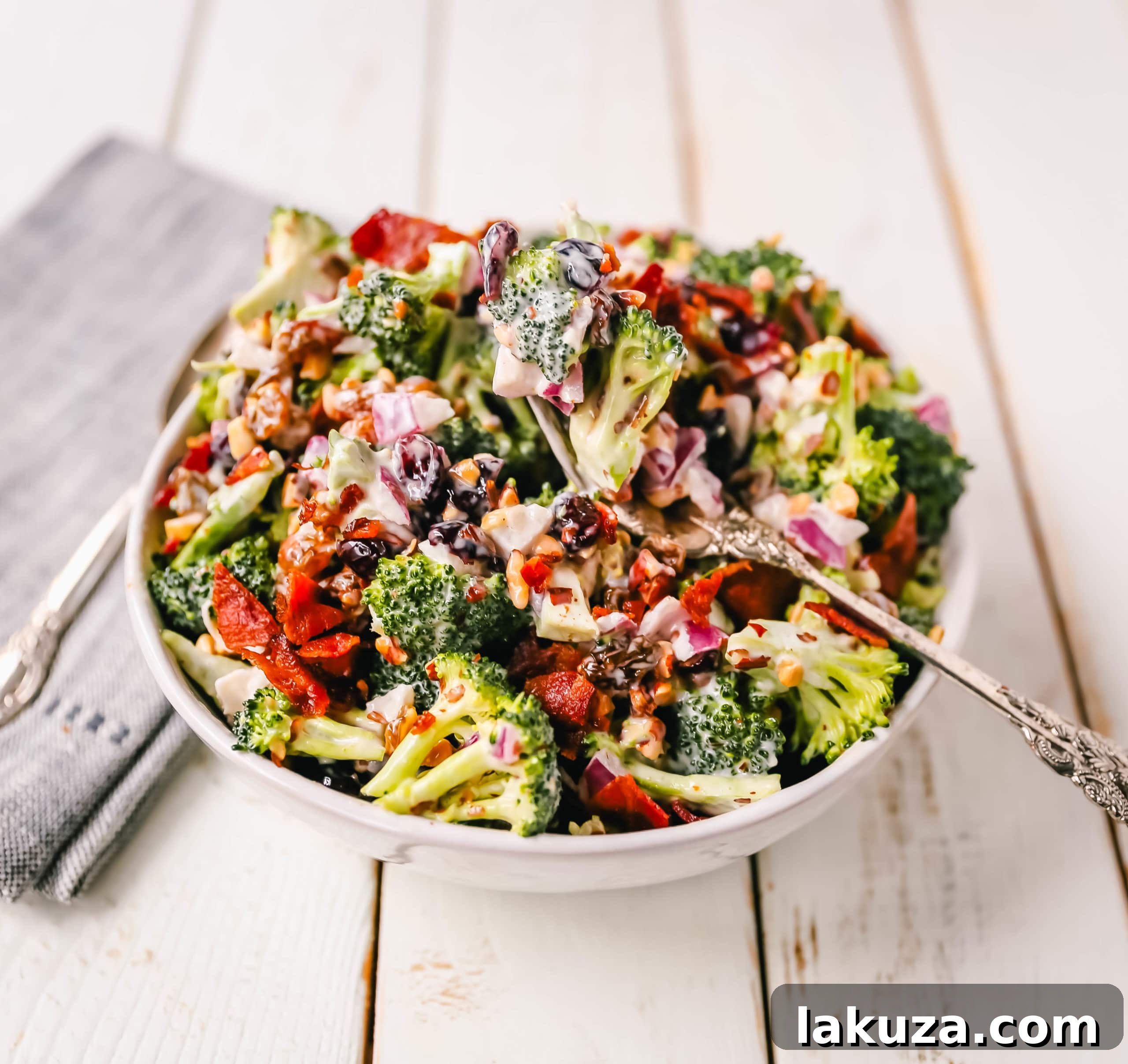 Broccoli Salad. Crunchy broccoli salad with crispy bacon, sweet dried cranberries, onion, nuts, tossed in a sweet and tangy dressing. A classic potluck side dish recipe! www.modernhoney.com #broccolisalad #sidedish #potluck #sides