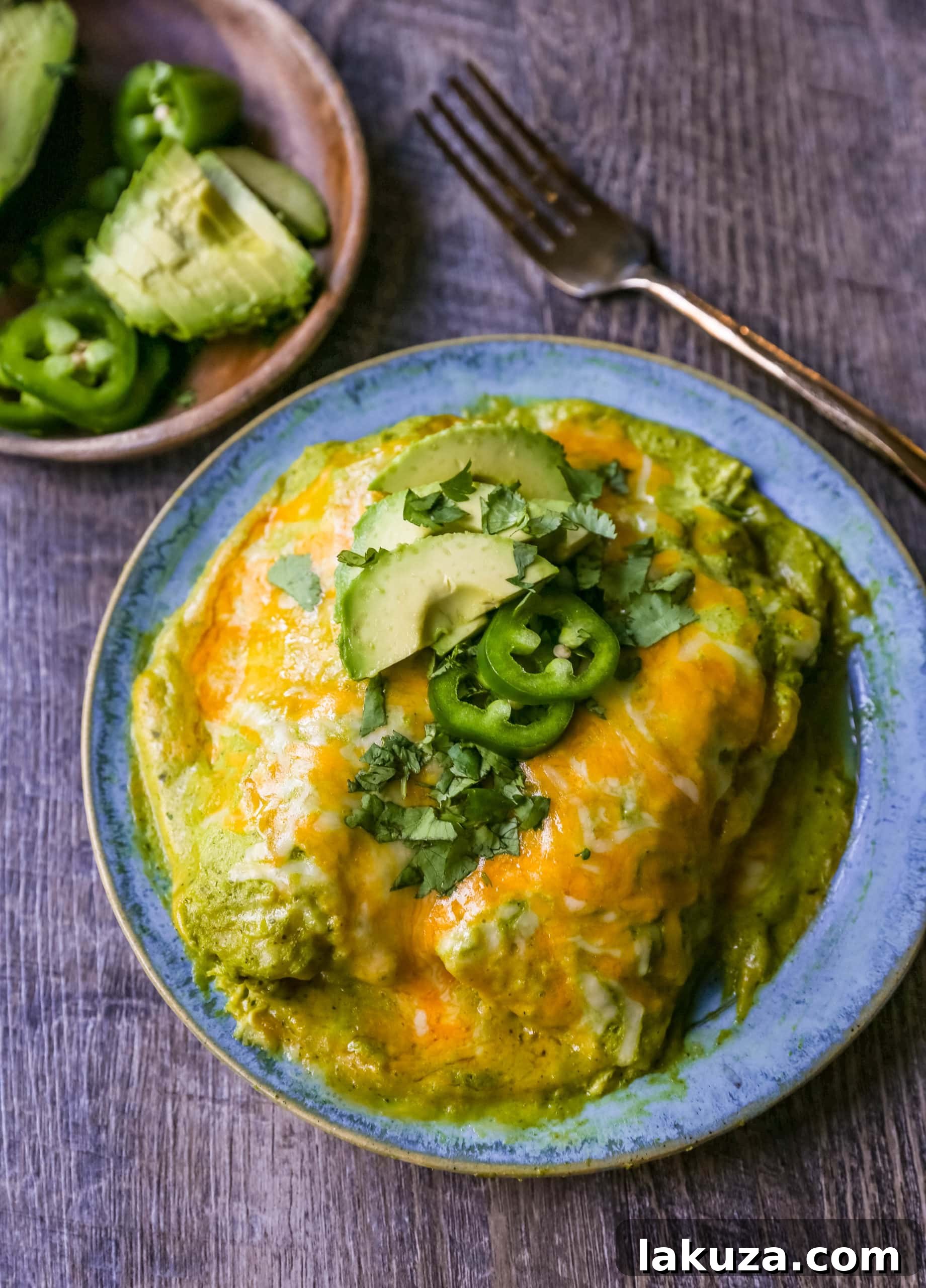Chicken Enchiladas Suizas with tender chicken, rich tomatillo-poblano sauce, and melted cheese, garnished with fresh cilantro and avocado slices.