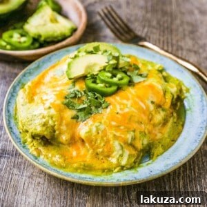 Chicken Enchiladas Suizas with tender chicken, rich tomatillo-poblano sauce, and melted cheese, garnished with fresh cilantro and avocado slices.