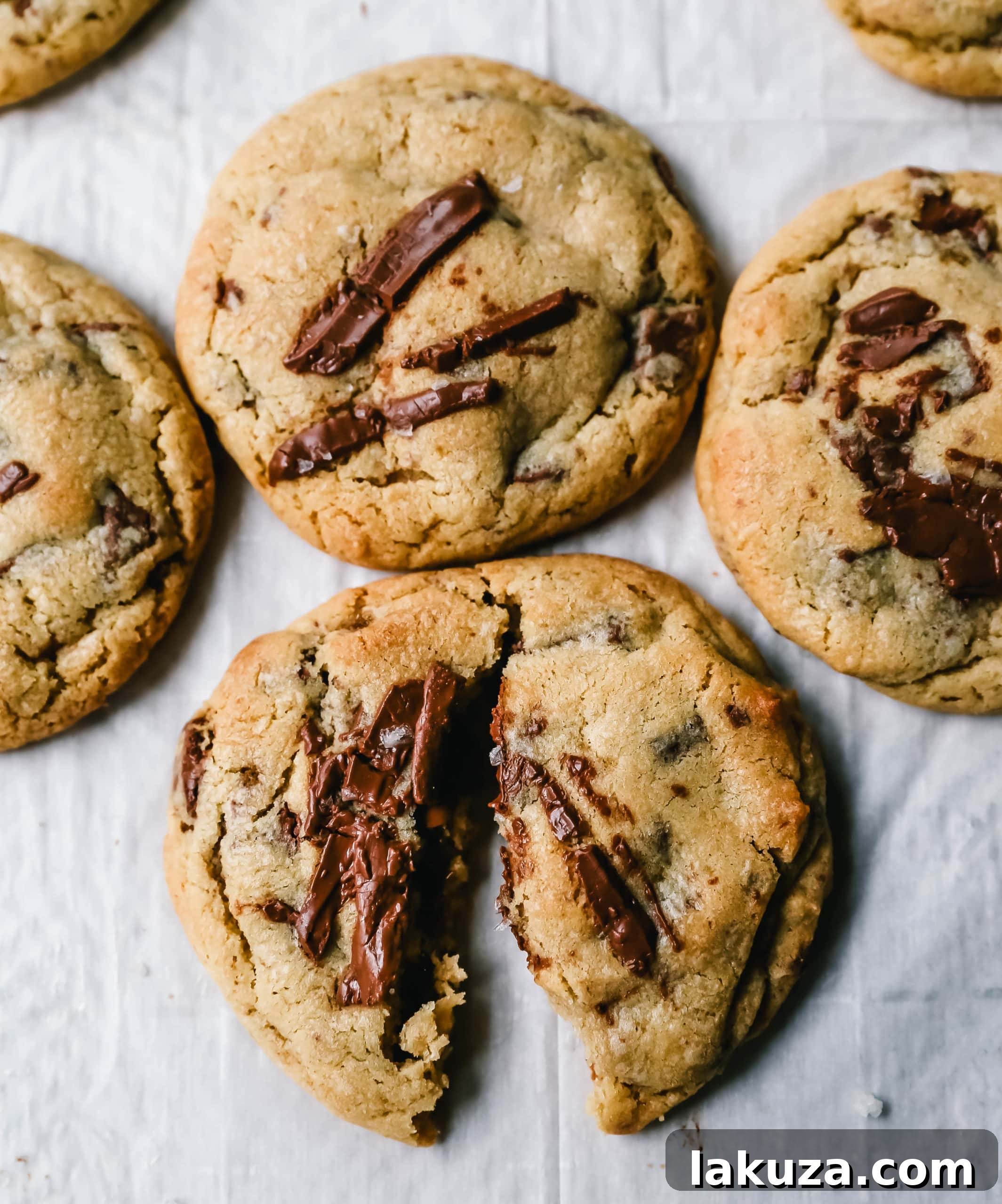 Freshly baked classic chocolate chip cookies cooling on a wire rack, with some still on the parchment paper.