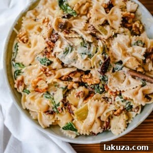 Creamy Bowtie Pasta with Sun-dried Tomatoes - A delicious 20-minute meal with a rich garlic cream sauce, artichoke hearts, Parmesan, and toasted walnuts.
