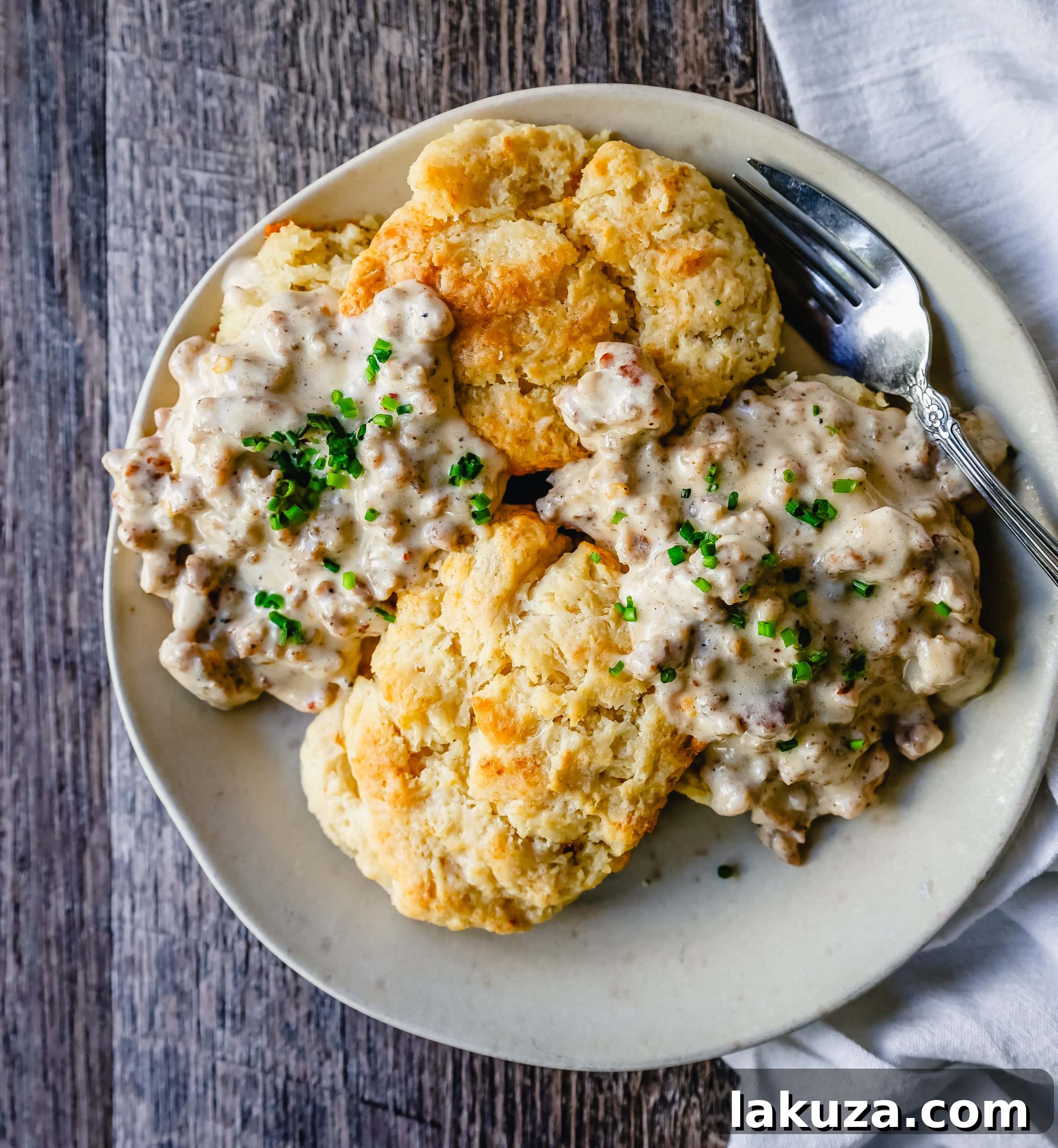 Closeup of homemade biscuits and gravy, showcasing the texture of flaky biscuits and the rich, creamy sausage gravy.